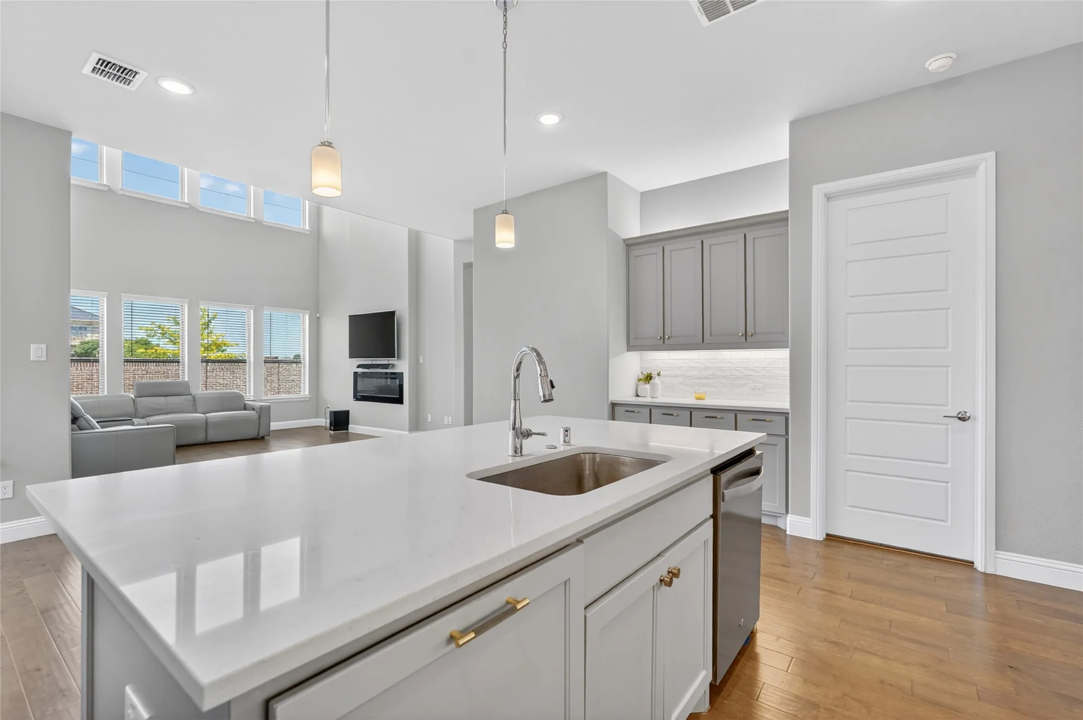 Kitchen island with a stainless steel sink, contemporary faucet, and integrated dishwasher