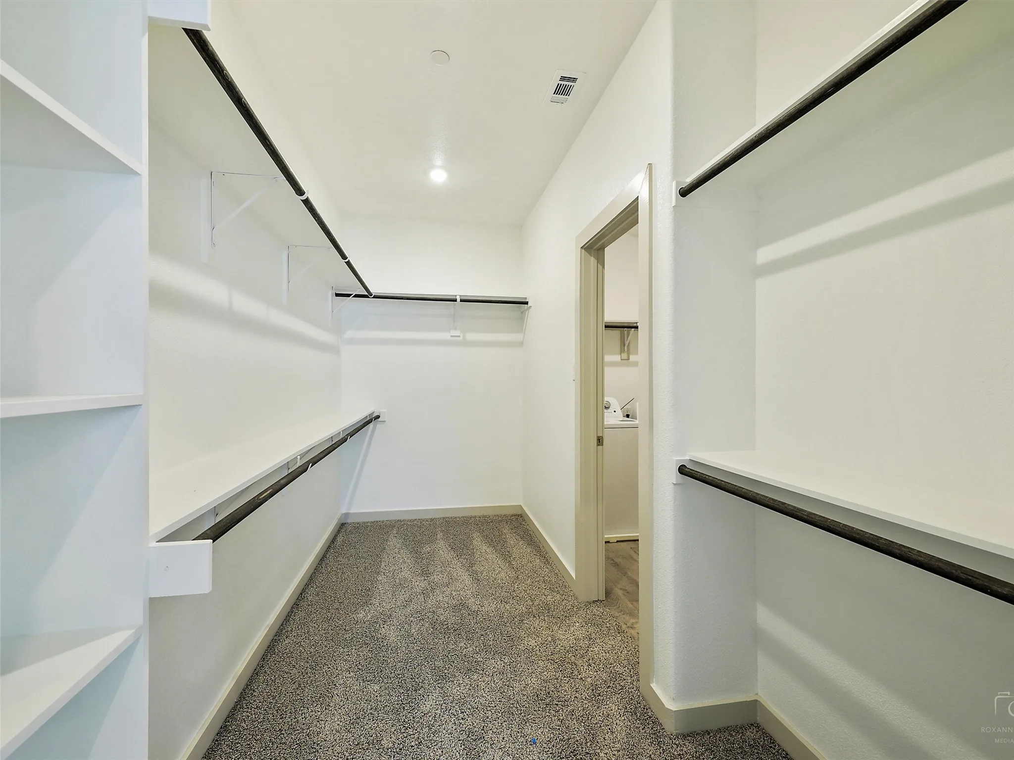 Walk-in closet featuring built-in shelving, hanging rods, recessed lighting, and carpet flooring