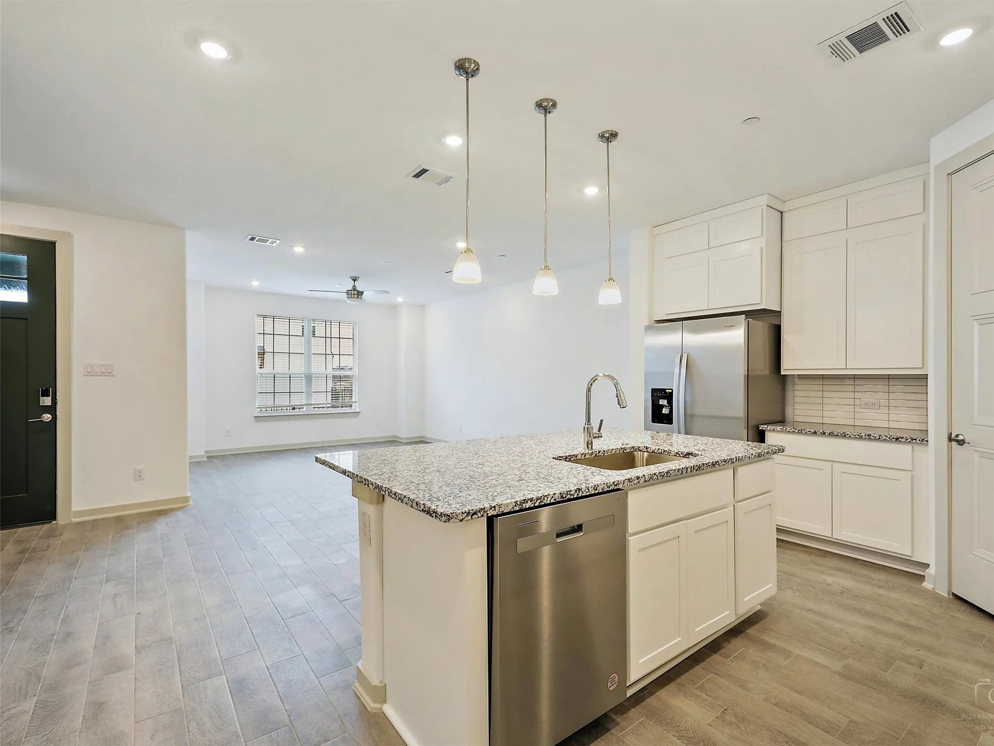 Kitchen island featuring a stainless steel sink with gooseneck faucet, integrated dishwasher, and granite countertop