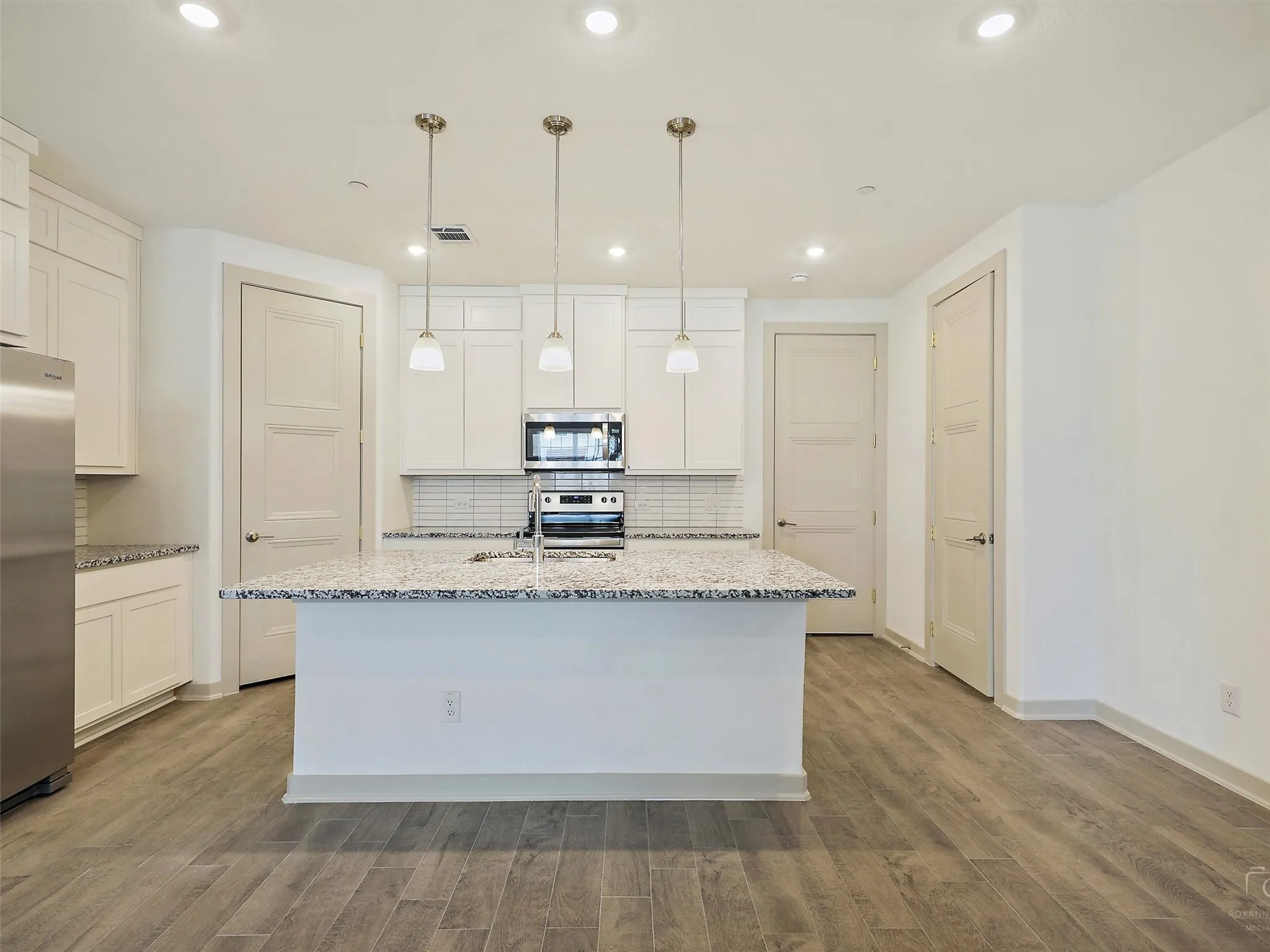 Modern kitchen featuring a central island with a double basin sink and a high-arc faucet