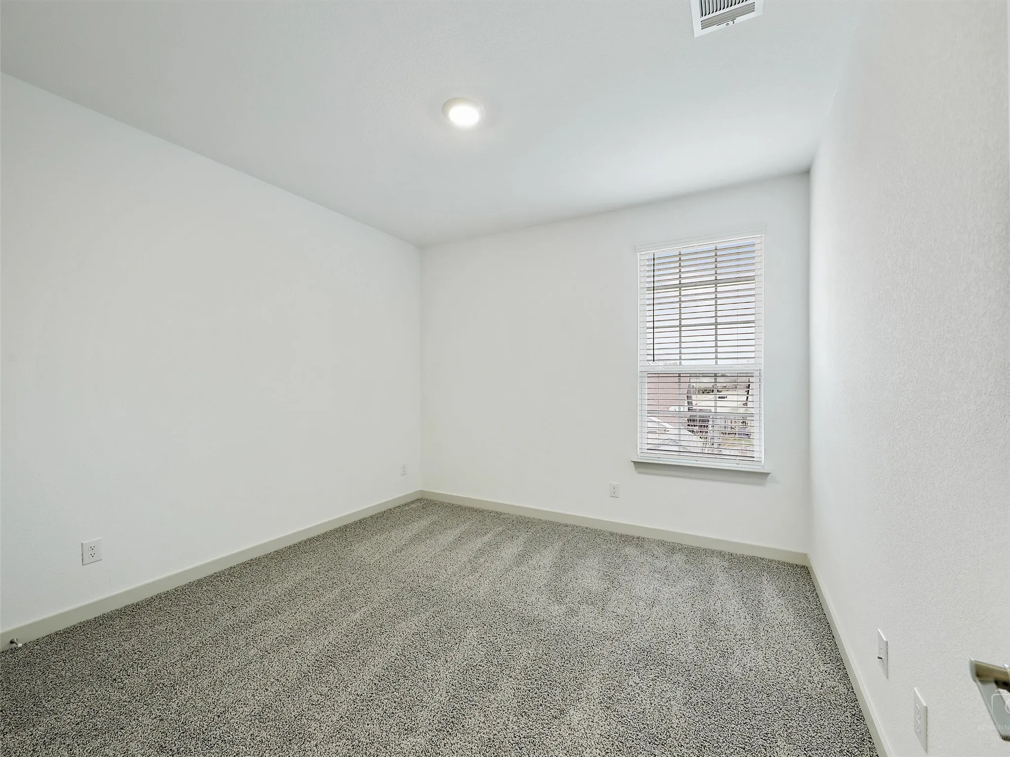 Carpeted room with a single window featuring horizontal blinds