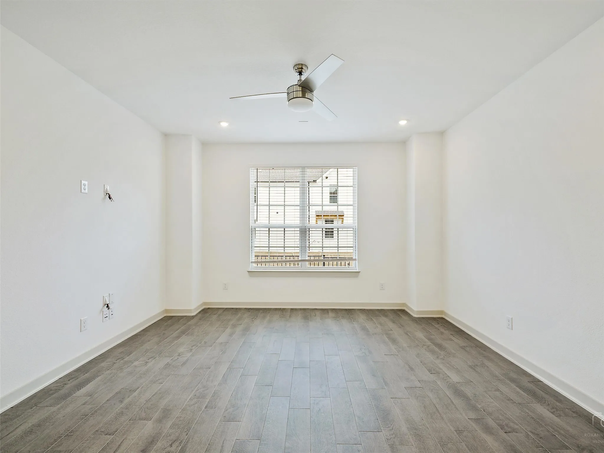 Spacious room featuring wood-finish flooring, a contemporary ceiling fan, and recessed lighting