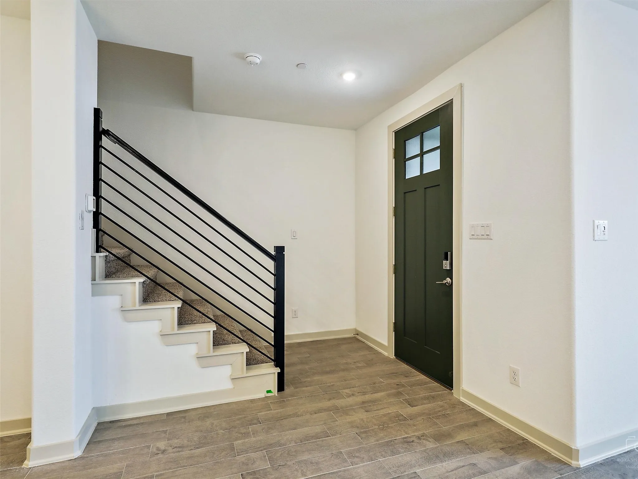 Entryway featuring a dark green front door with glass lites, a smart lock, and wood-finish tile flooring