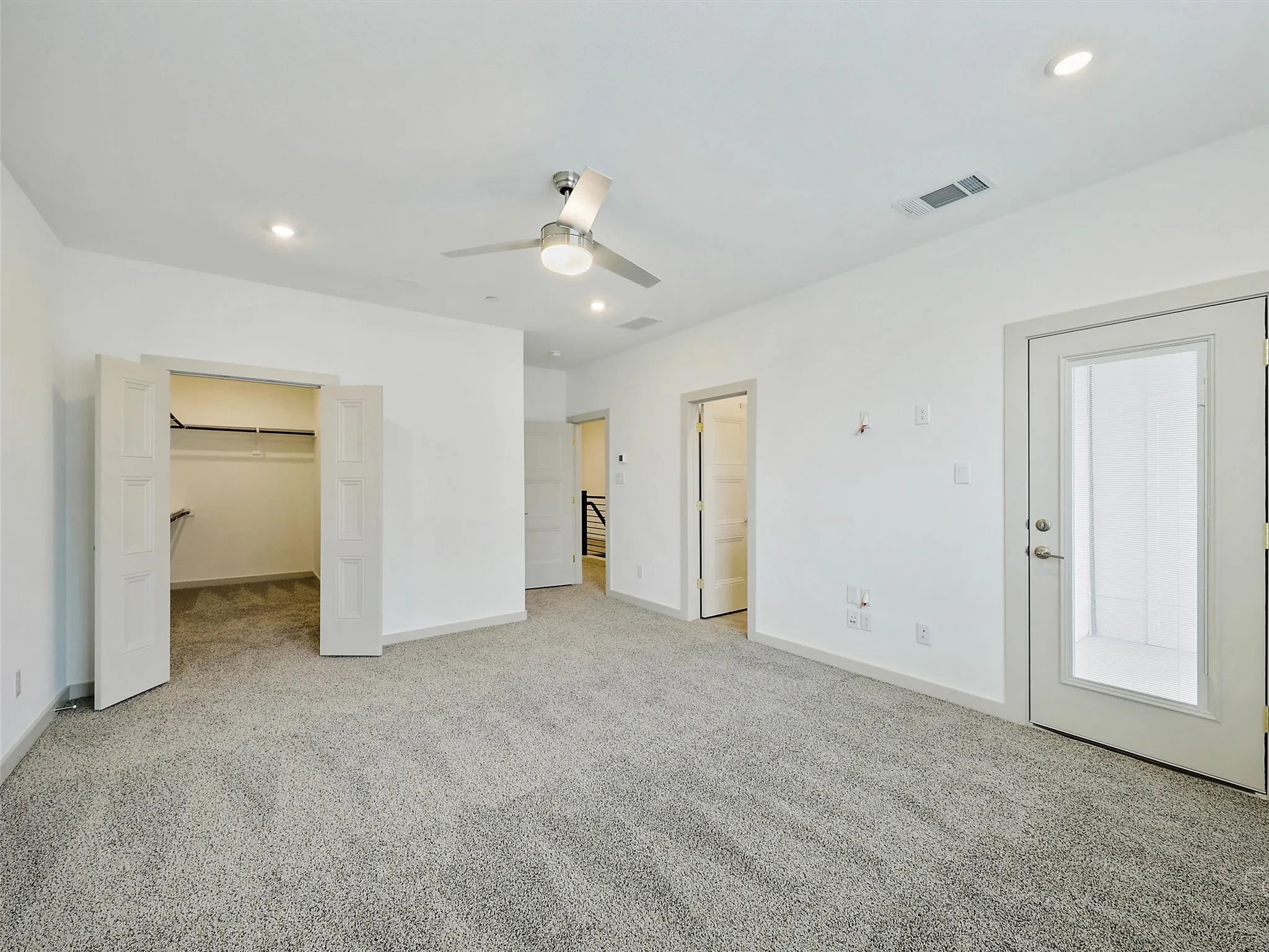 Spacious room with gray textured carpeting, a ceiling fan with integrated lighting, and recessed ceiling lights