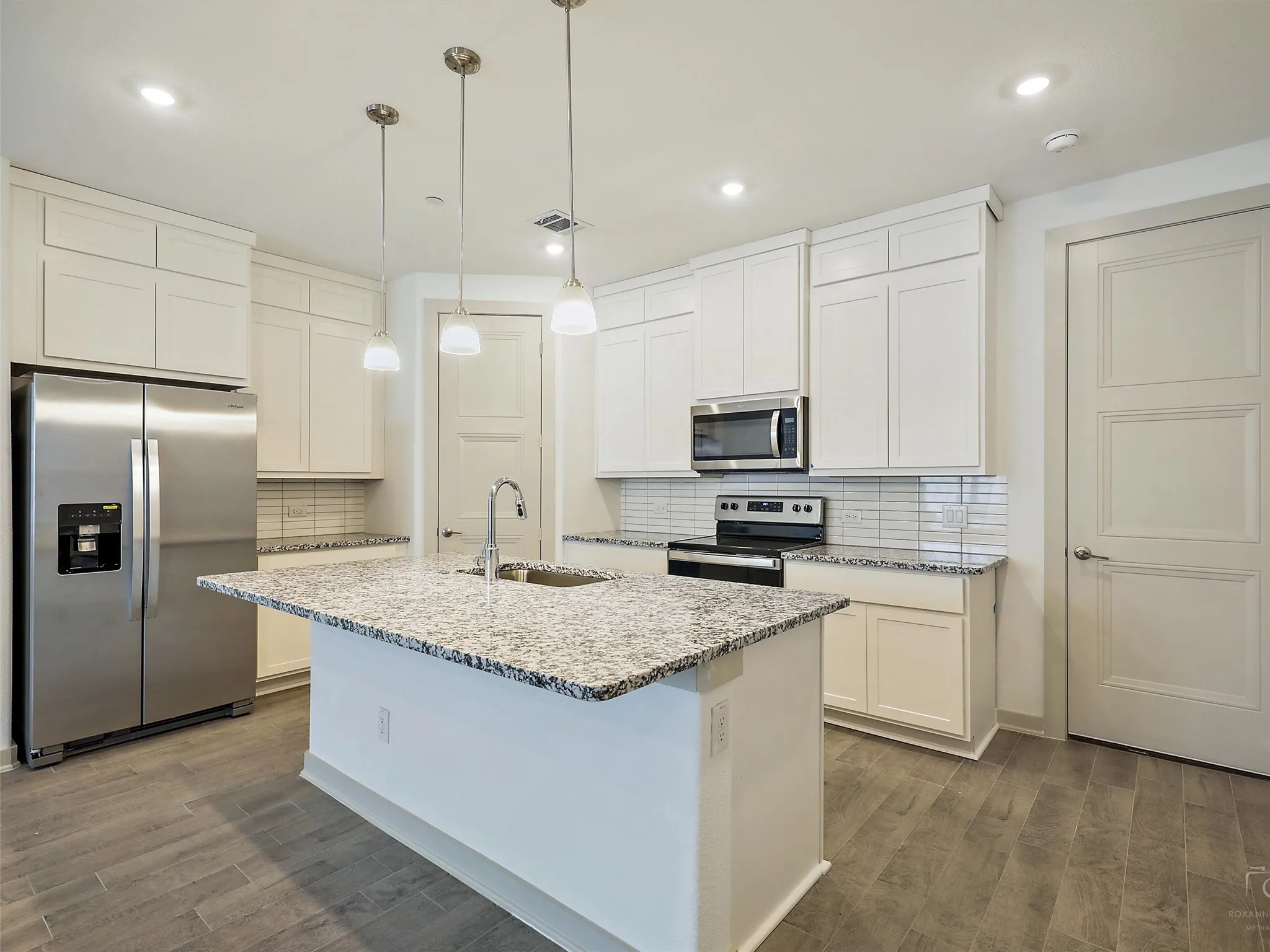 Kitchen featuring a central island with an undermount sink and three pendant lights