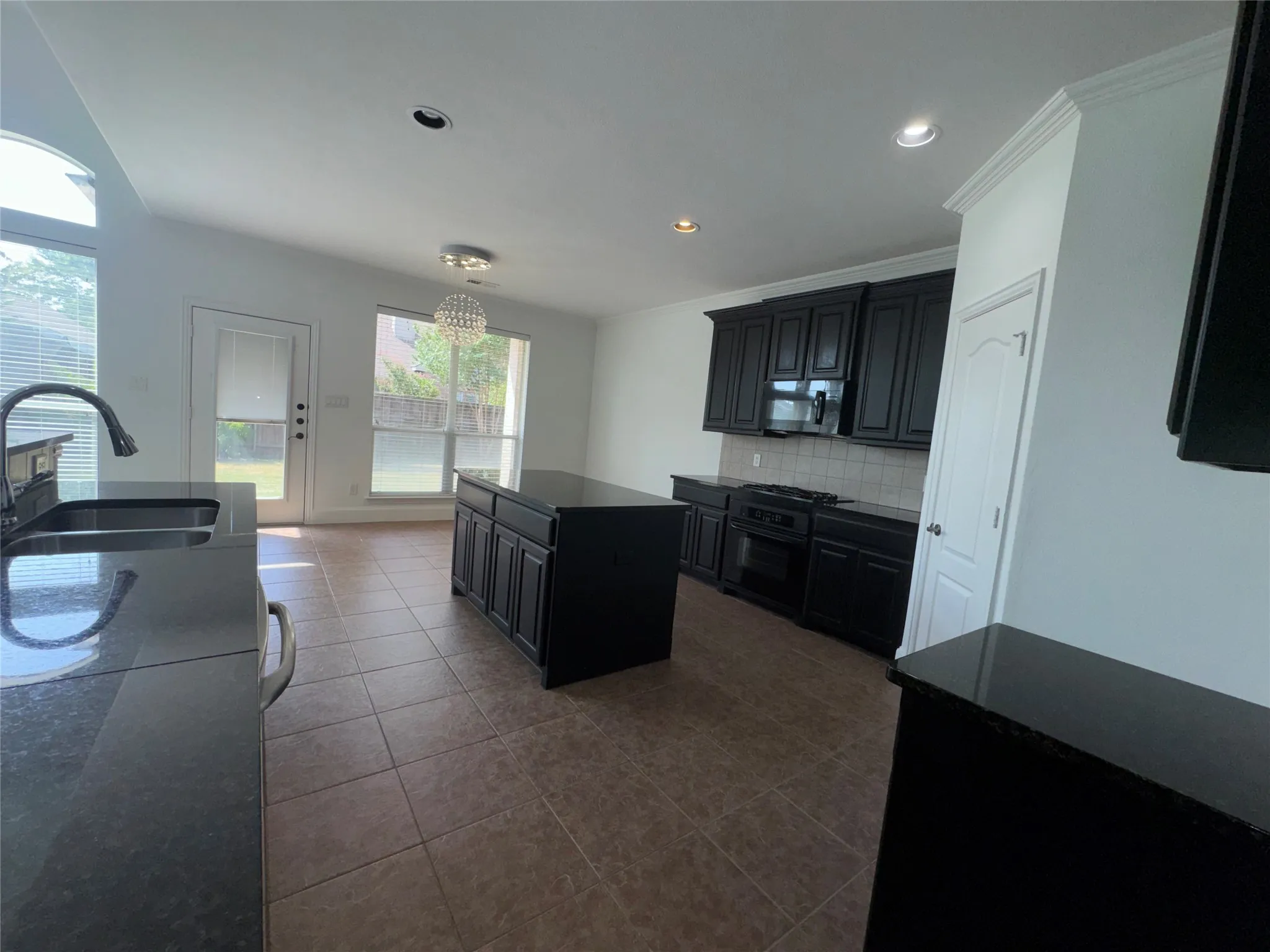 Spacious kitchen featuring dark cabinetry, stainless steel appliances, and an island with seating