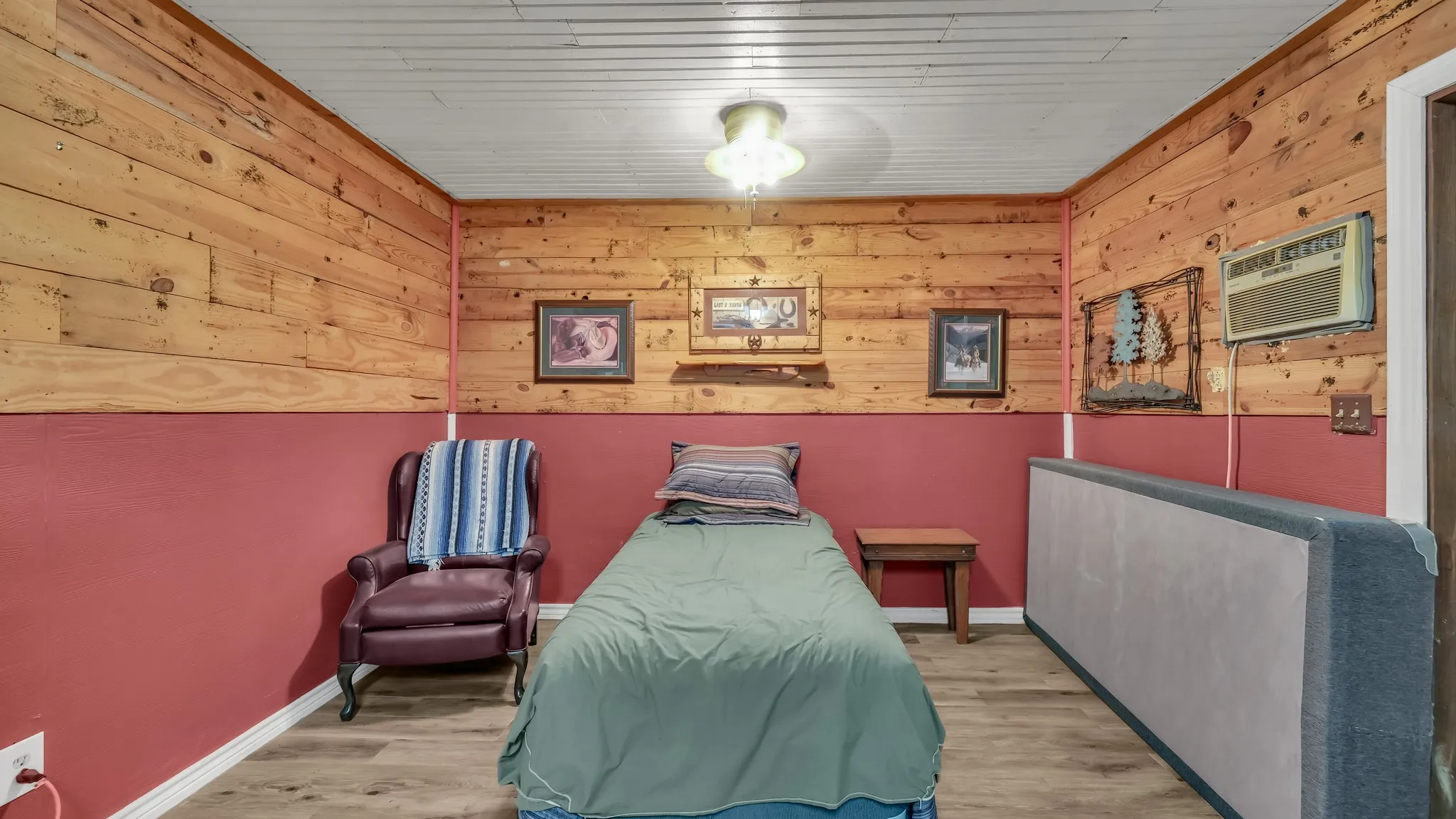Room featuring wood plank wall accents, red painted wainscoting, and wood-finish flooring
