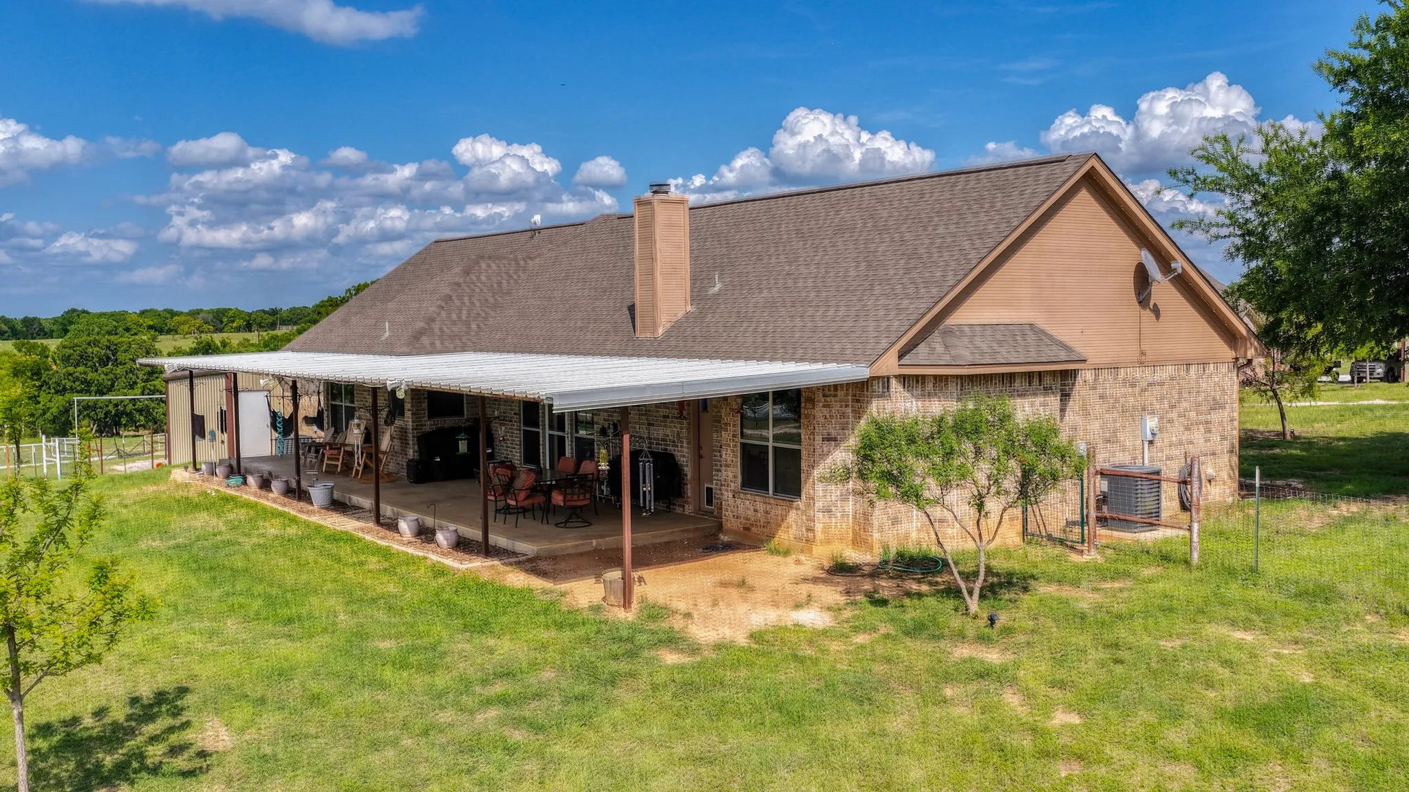 Expansive covered patio featuring a concrete slab, multiple support columns, and a full-length awning