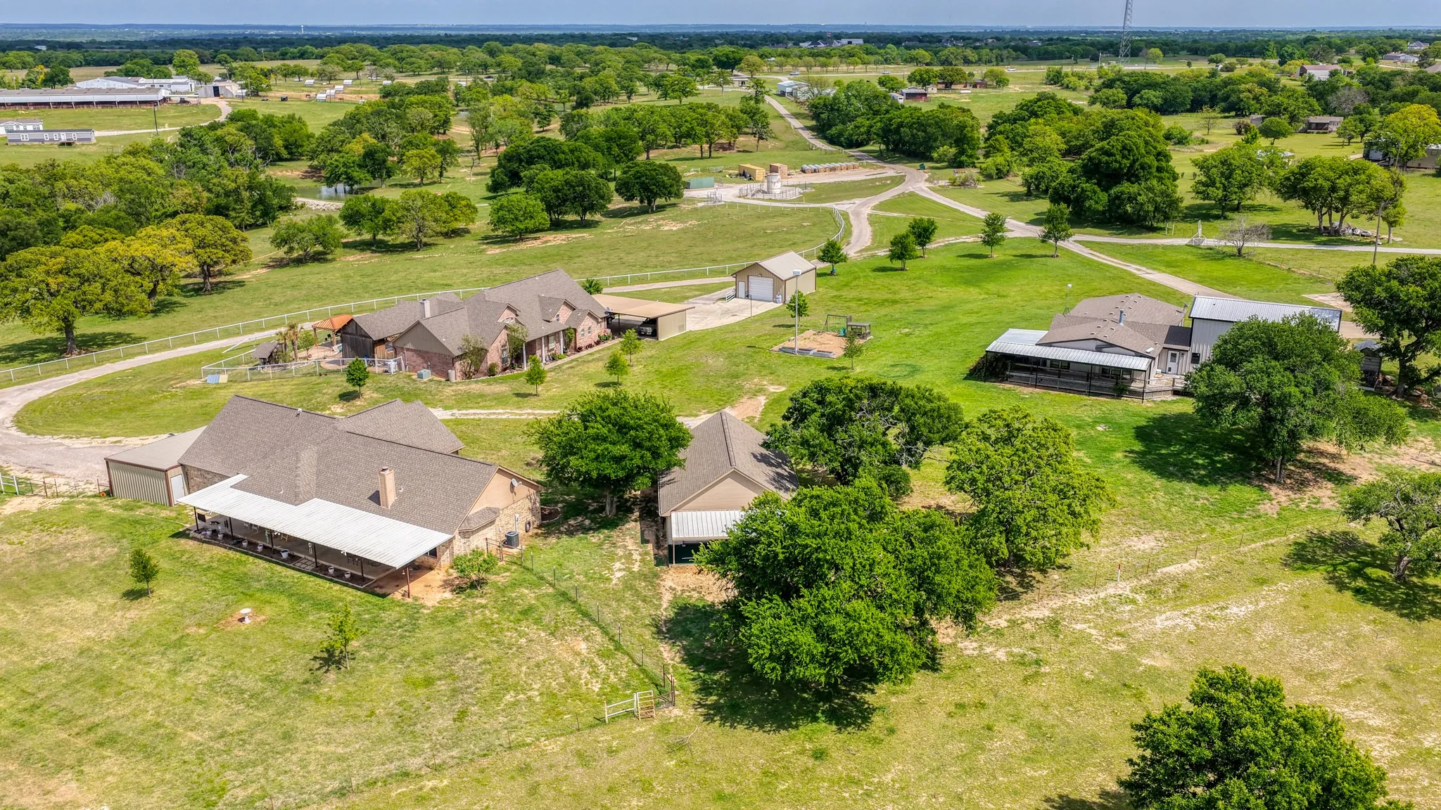 Expansive property featuring multiple structures, mature trees, and open green spaces