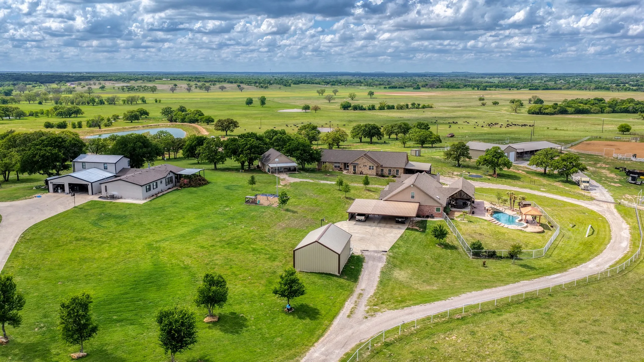 Expansive property featuring multiple structures, a main residence with an outdoor pool, a secondary dwelling, and an additional outbuilding