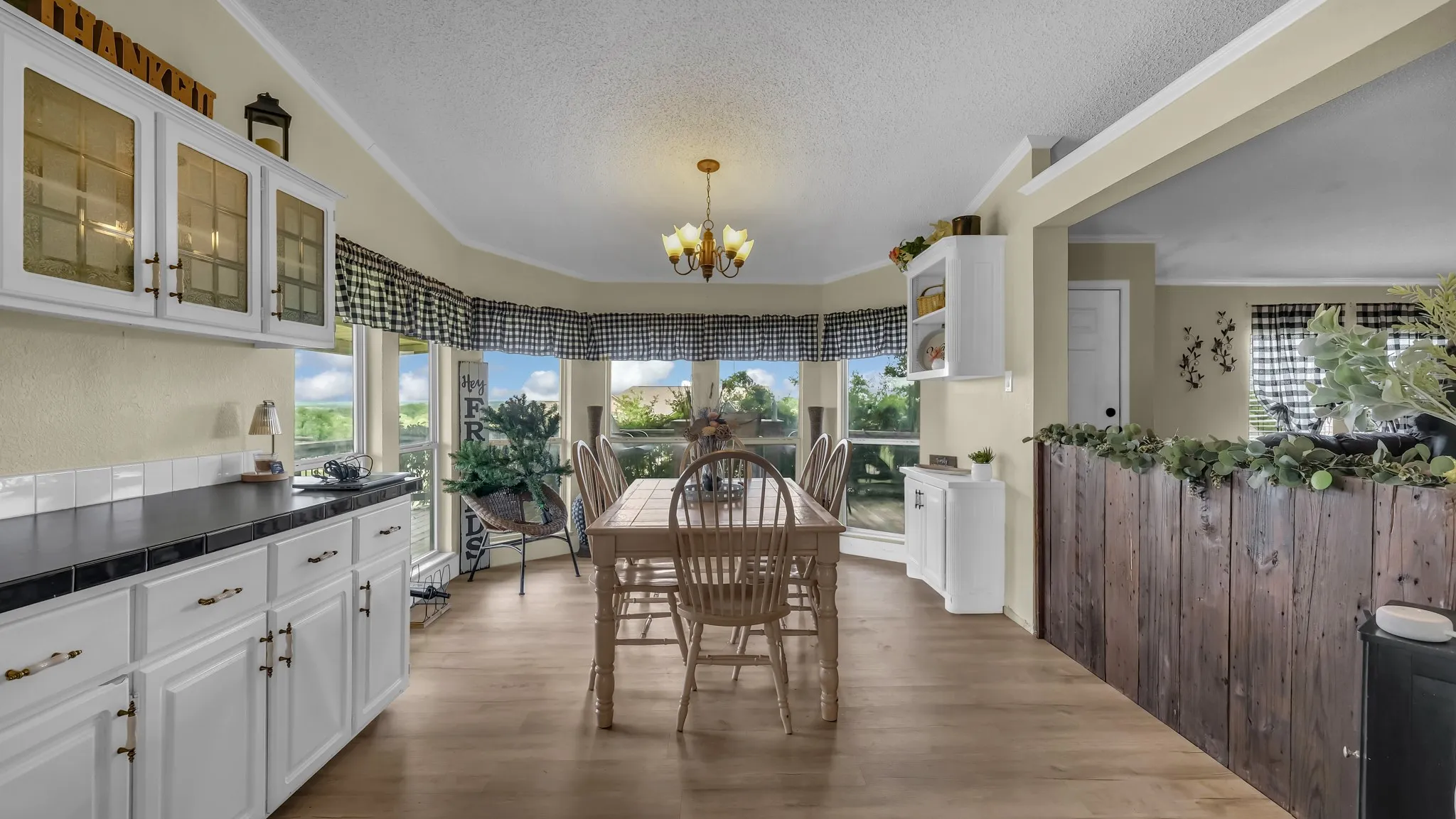 Dining area featuring wood-finish flooring, a bay window with multiple panes, and a chandelier light fixture