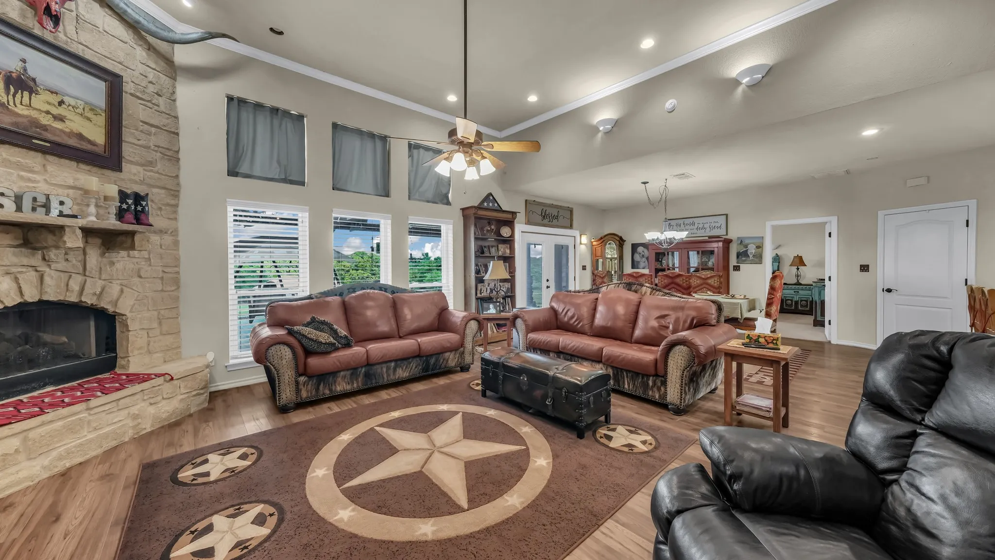 Spacious living area featuring a floor-to-ceiling stone fireplace, wood-finish flooring, recessed lighting, and multiple windows