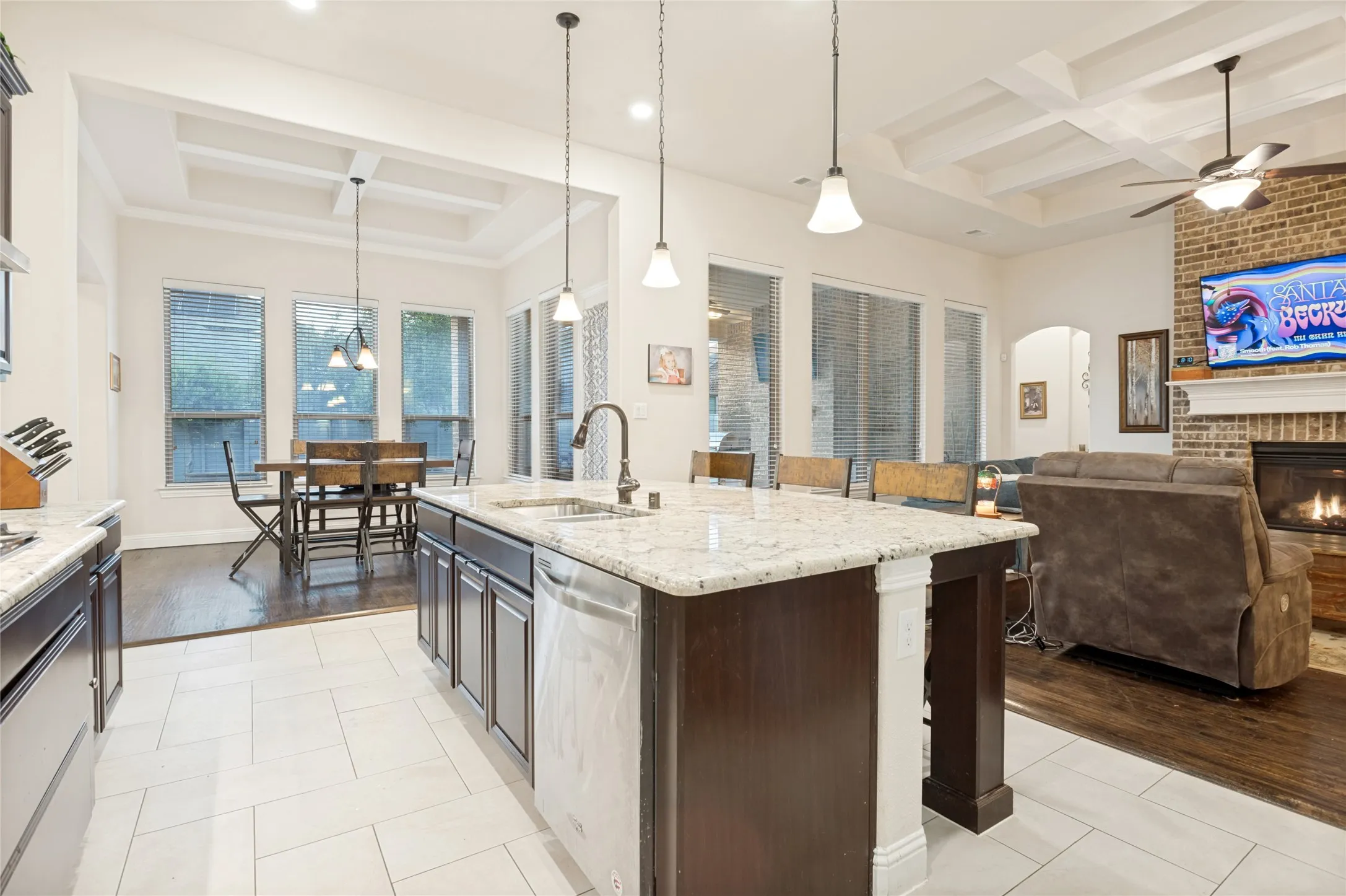 Spacious open-concept kitchen featuring a large island with granite countertops, dark wood cabinetry, and pendant lighting