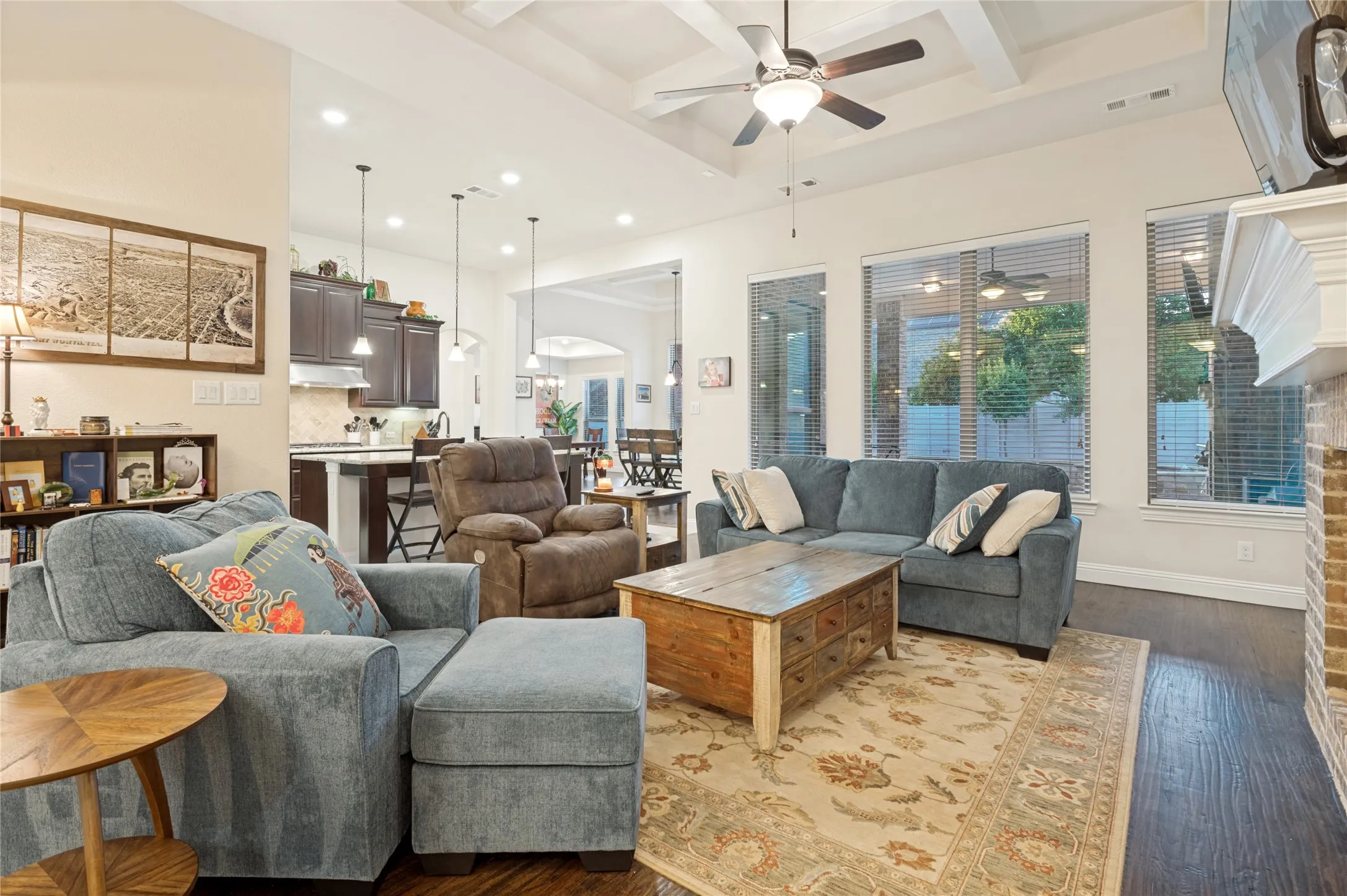 Open-concept living area featuring wood-finish flooring, a coffered ceiling, and a ceiling fan