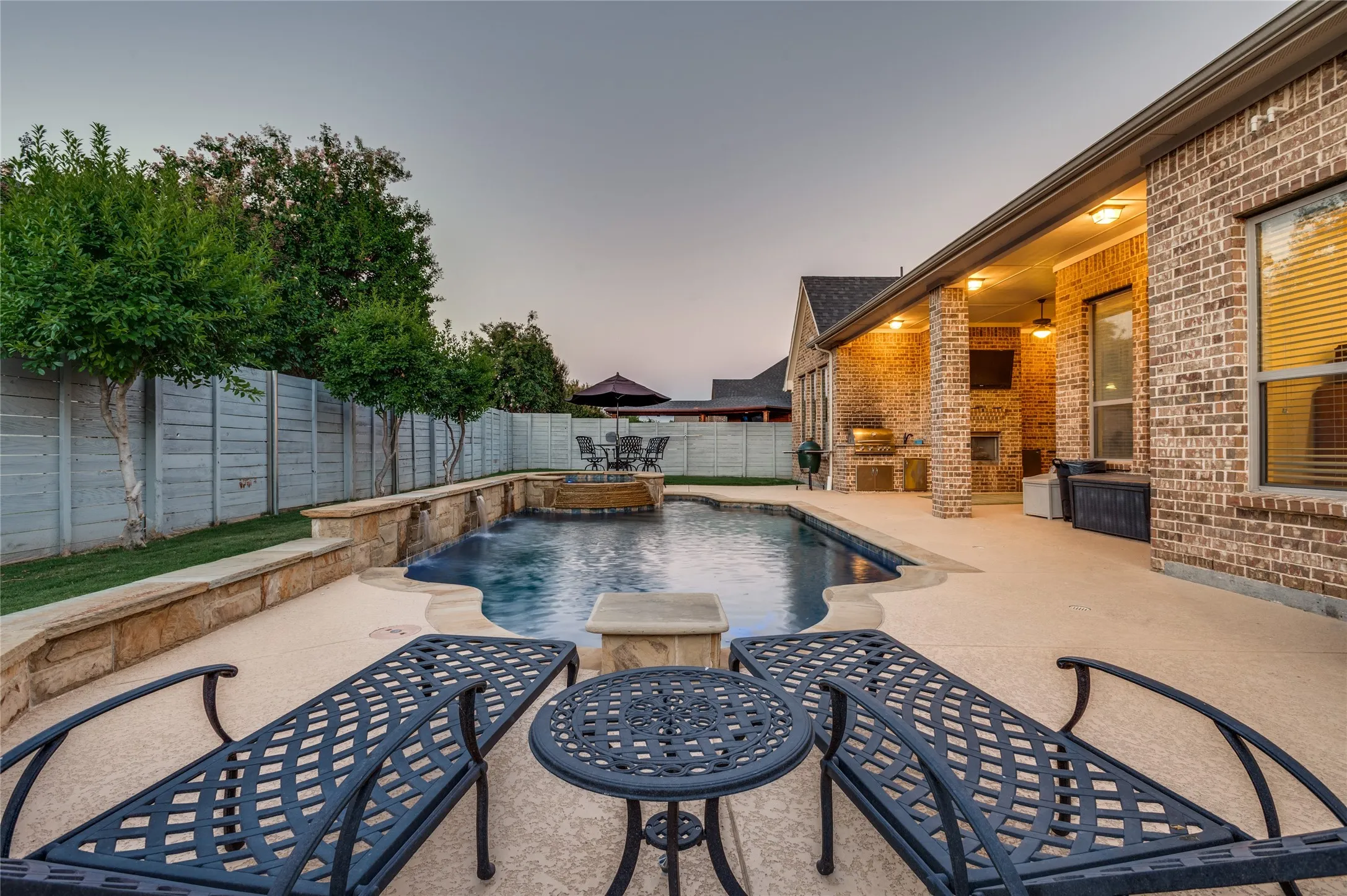 Backyard oasis featuring a freeform pool with stone coping, integrated spa, and rock waterfall accents