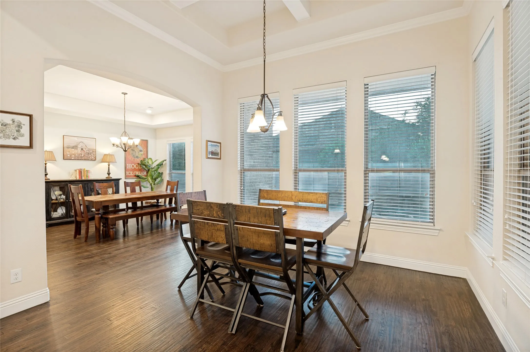 Dining area featuring wood-finish flooring, a coffered ceiling, and multiple windows with blinds