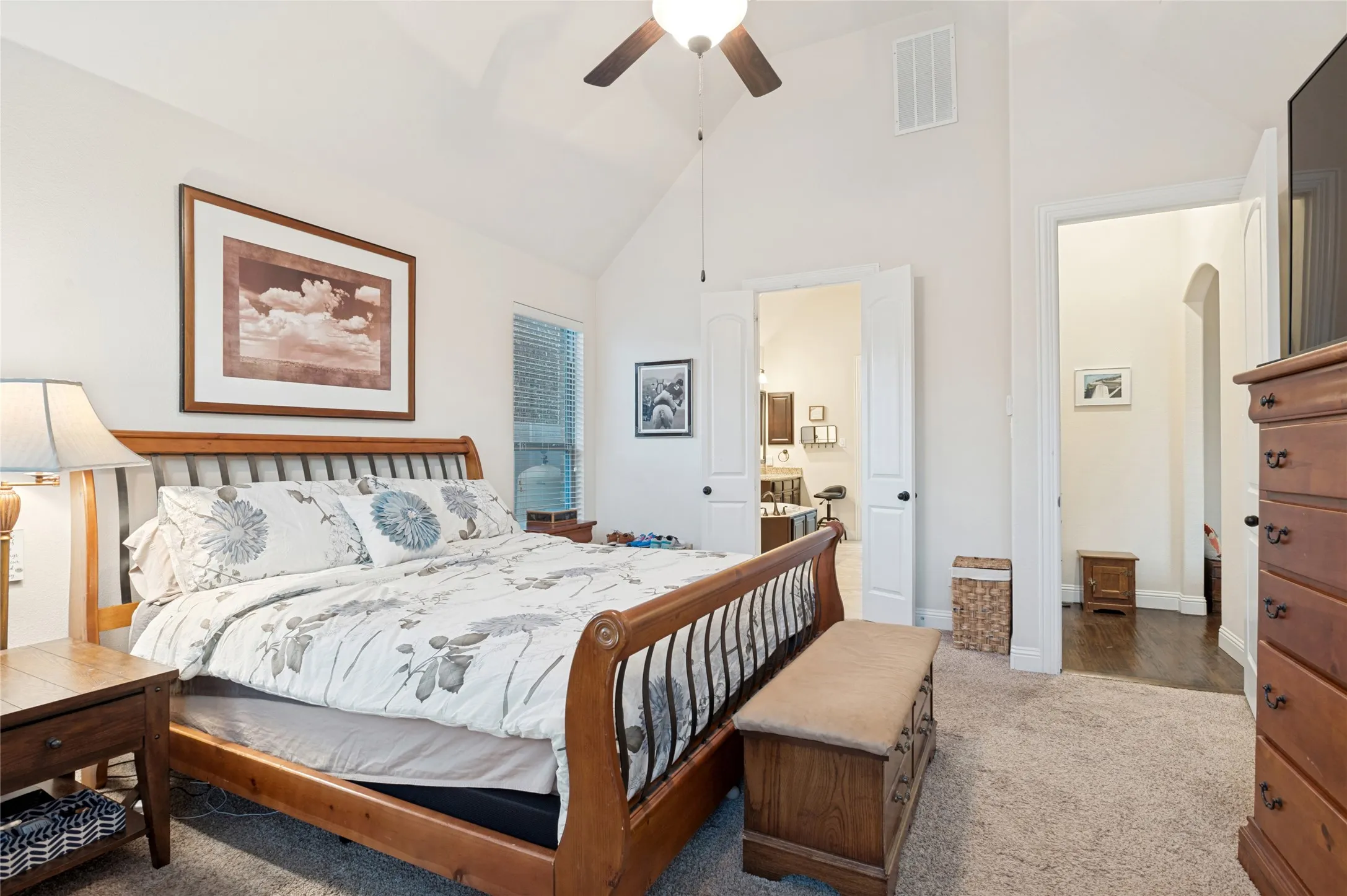 Vaulted ceiling bedroom with a ceiling fan, carpet flooring, and an arched entryway