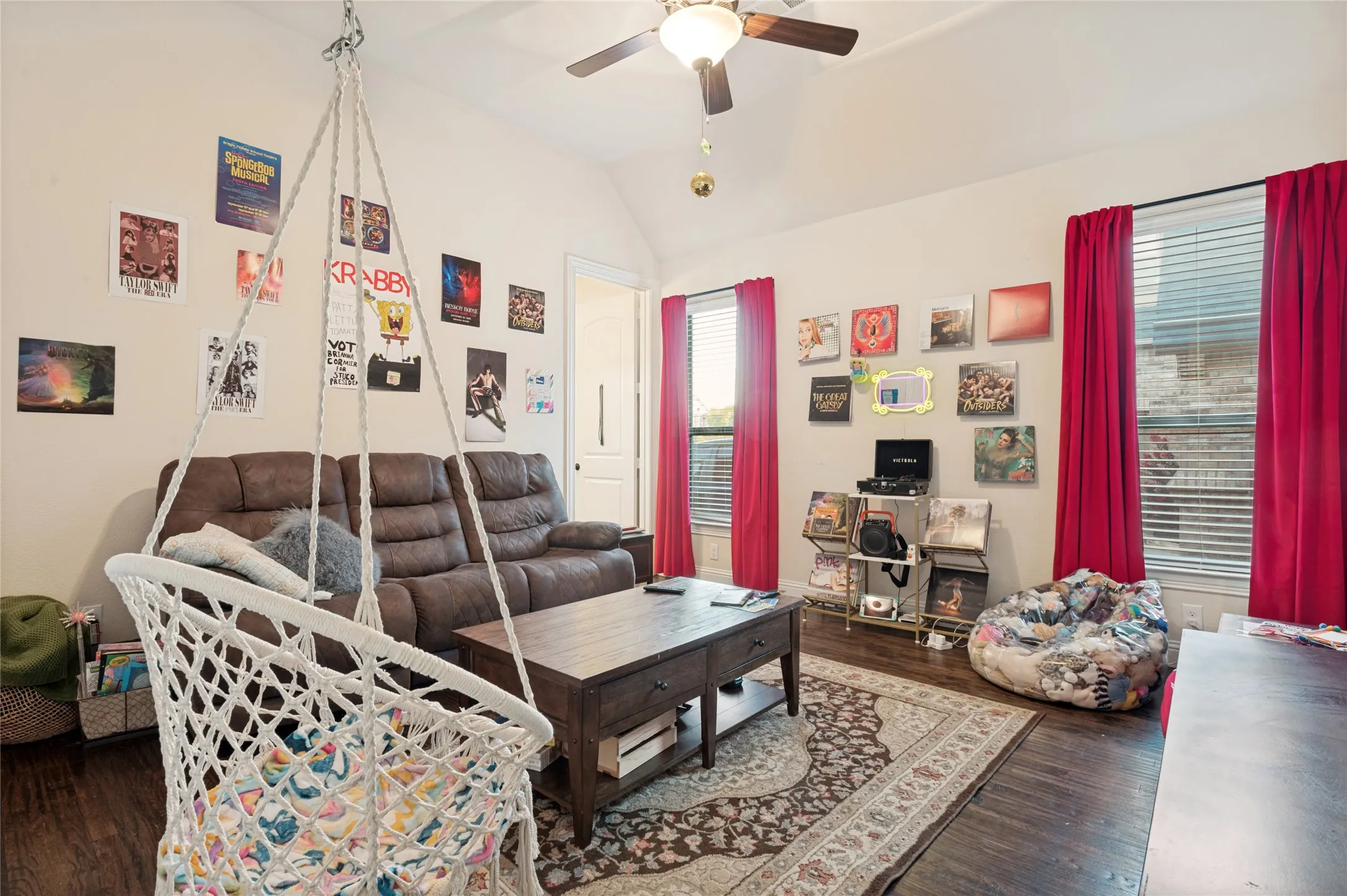 Spacious room featuring vaulted ceilings, wood-finish flooring, and two large windows with blinds