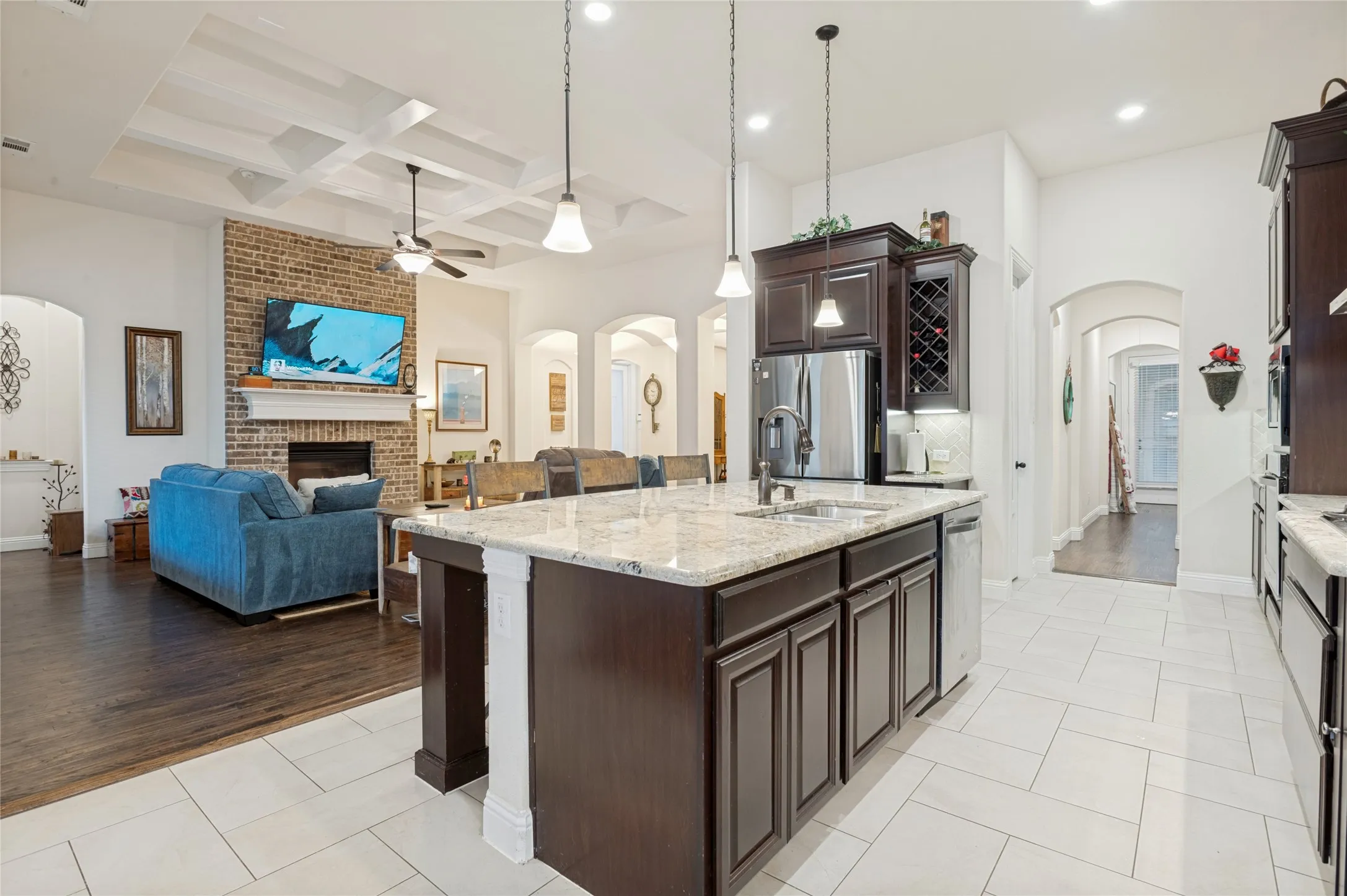 Kitchen island with a granite countertop, undermount sink, and dark wood cabinetry