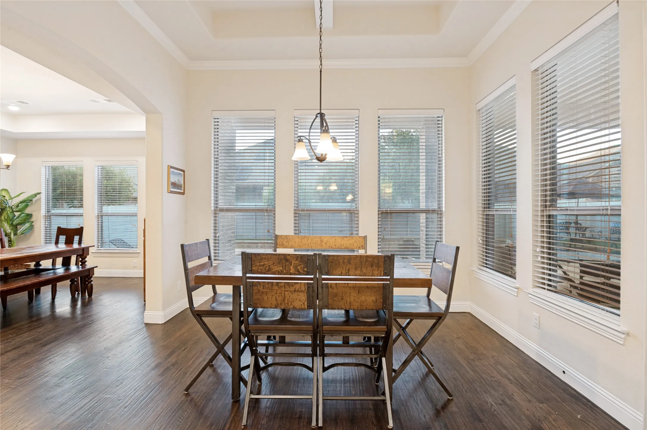 Dining area featuring a coffered ceiling, dark wood-finish flooring, and multiple windows with blinds