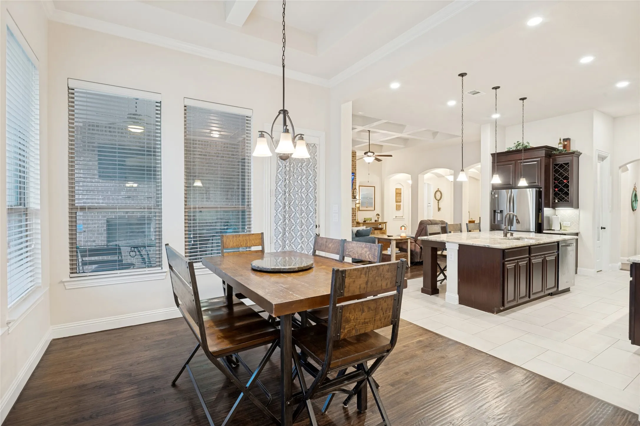 Open-concept interior featuring wood-finish flooring in the foreground, transitioning to light-toned tile flooring
