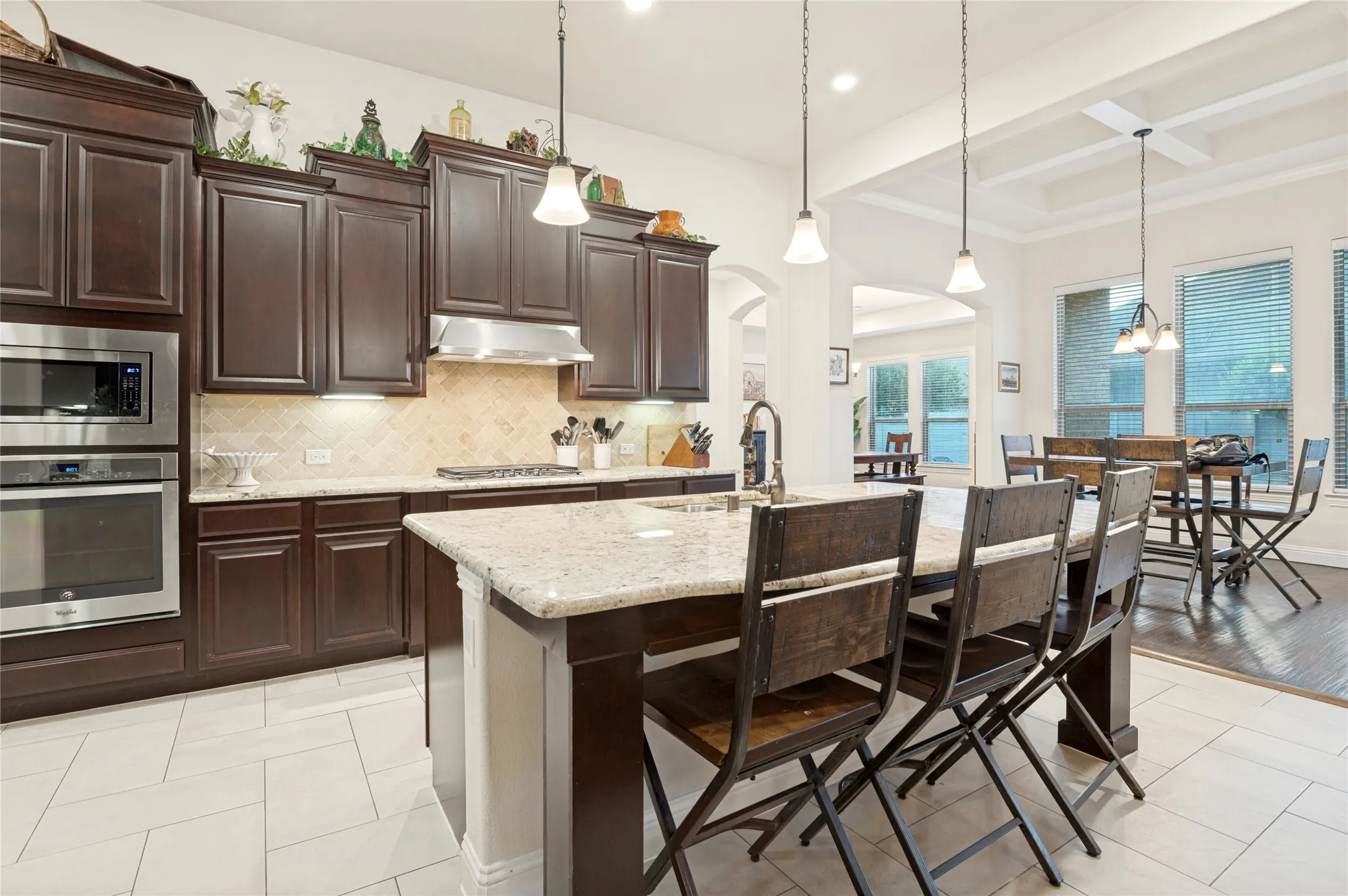 Gourmet kitchen featuring dark wood cabinetry, stainless steel appliances, a patterned tile backsplash, and light-toned granite countertops