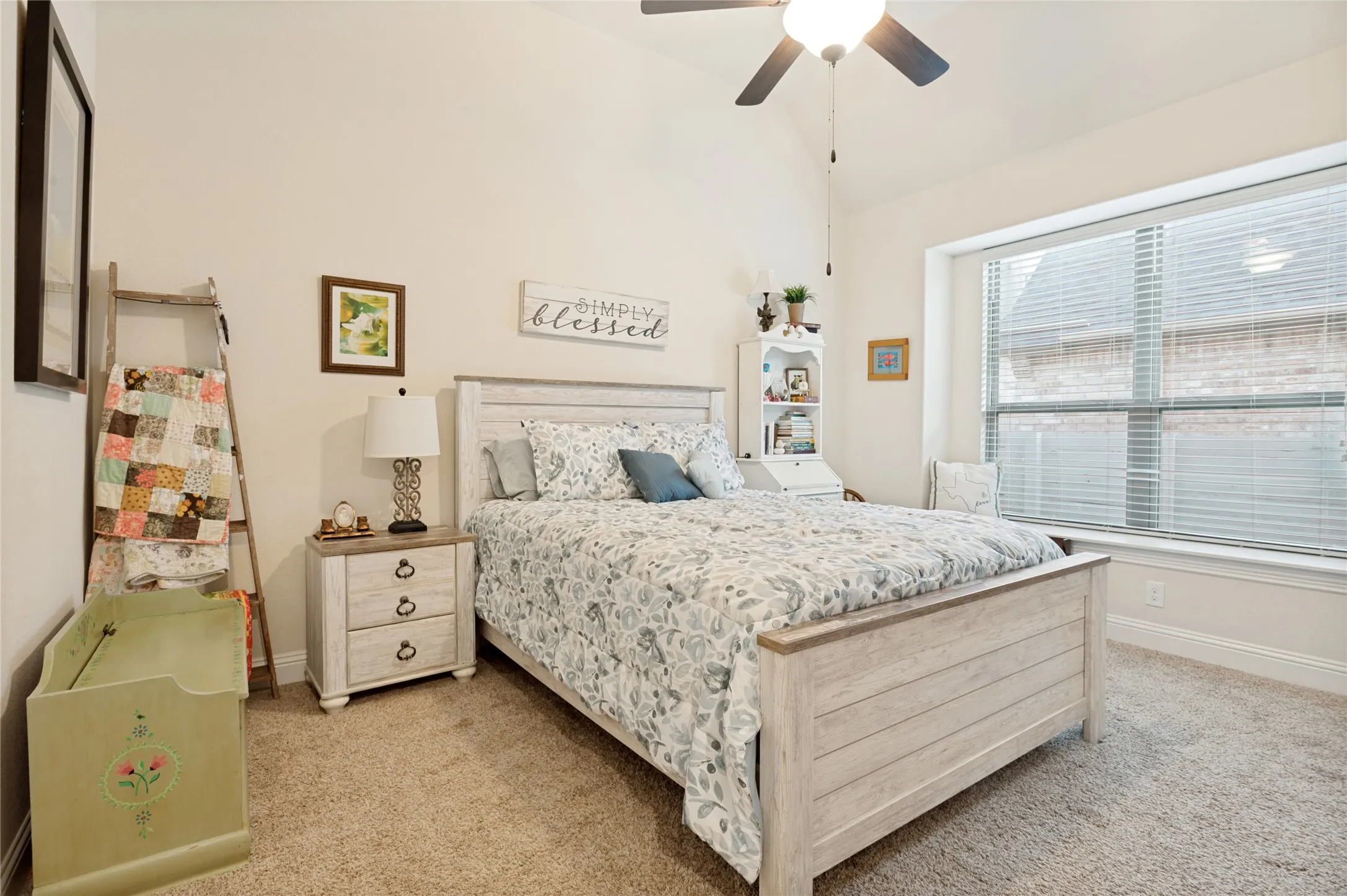 Carpeted room featuring a vaulted ceiling with a mounted ceiling fan, a large bay window with blinds, and light-toned walls