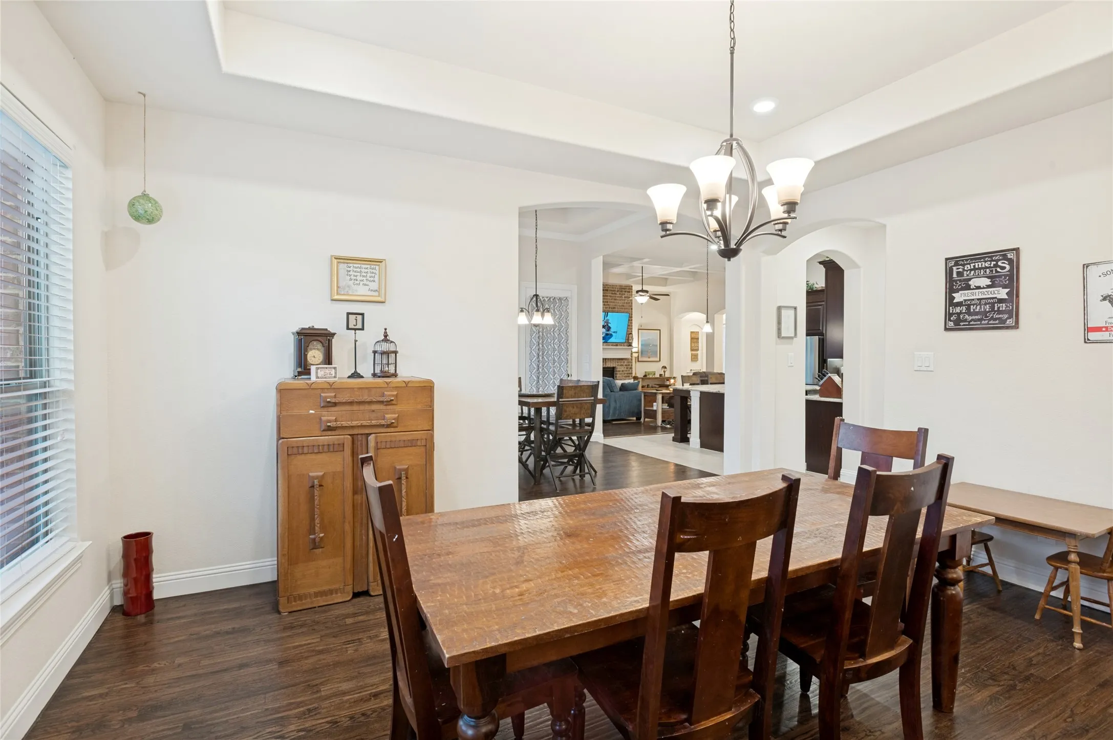 Spacious dining area featuring wood-finish flooring, a tray ceiling, and an arched entryway