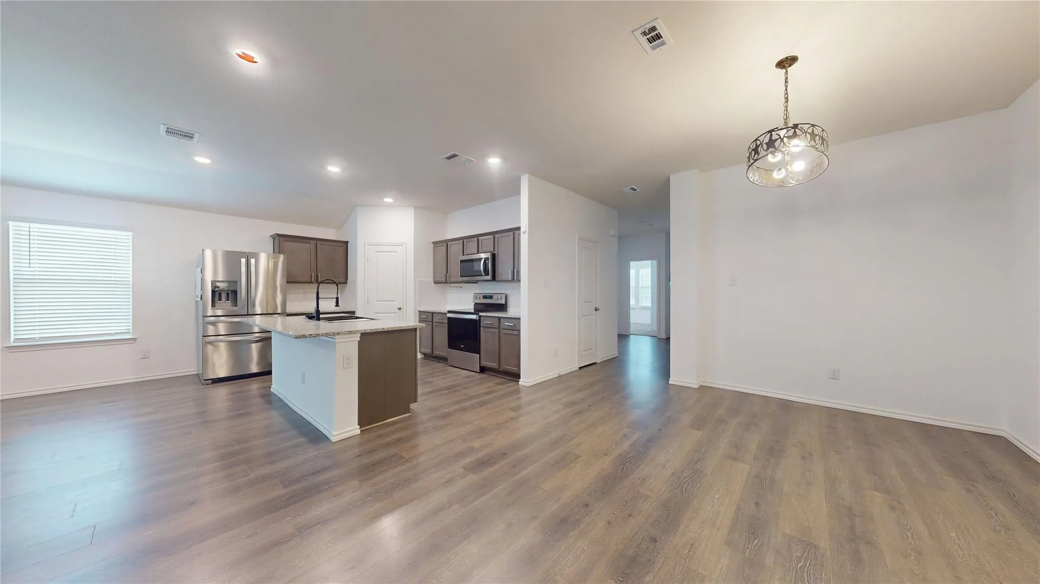 Open-concept living area with wood-finish flooring, recessed lighting, and a window with blinds