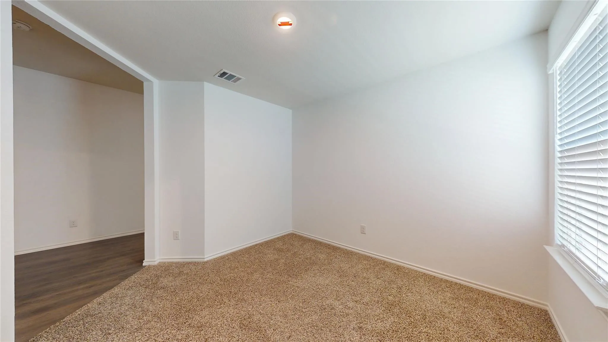 Neutral wall finishes with a window featuring horizontal blinds