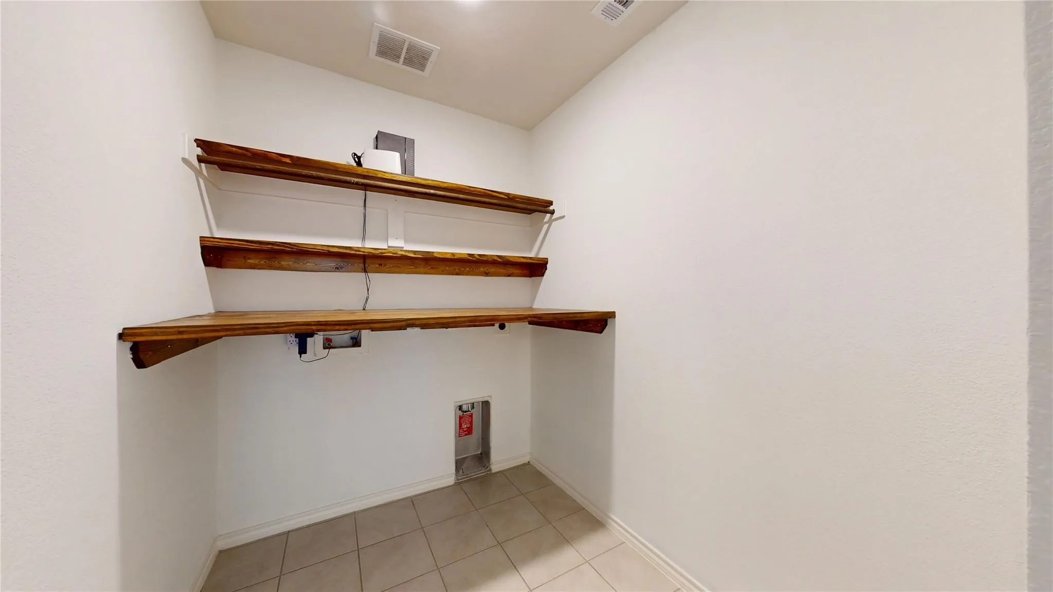 Laundry area featuring light-toned tile flooring and white walls