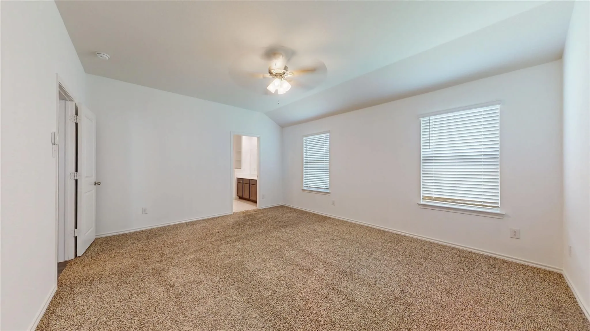 Carpeted room with vaulted ceilings and a ceiling fan with integrated lighting