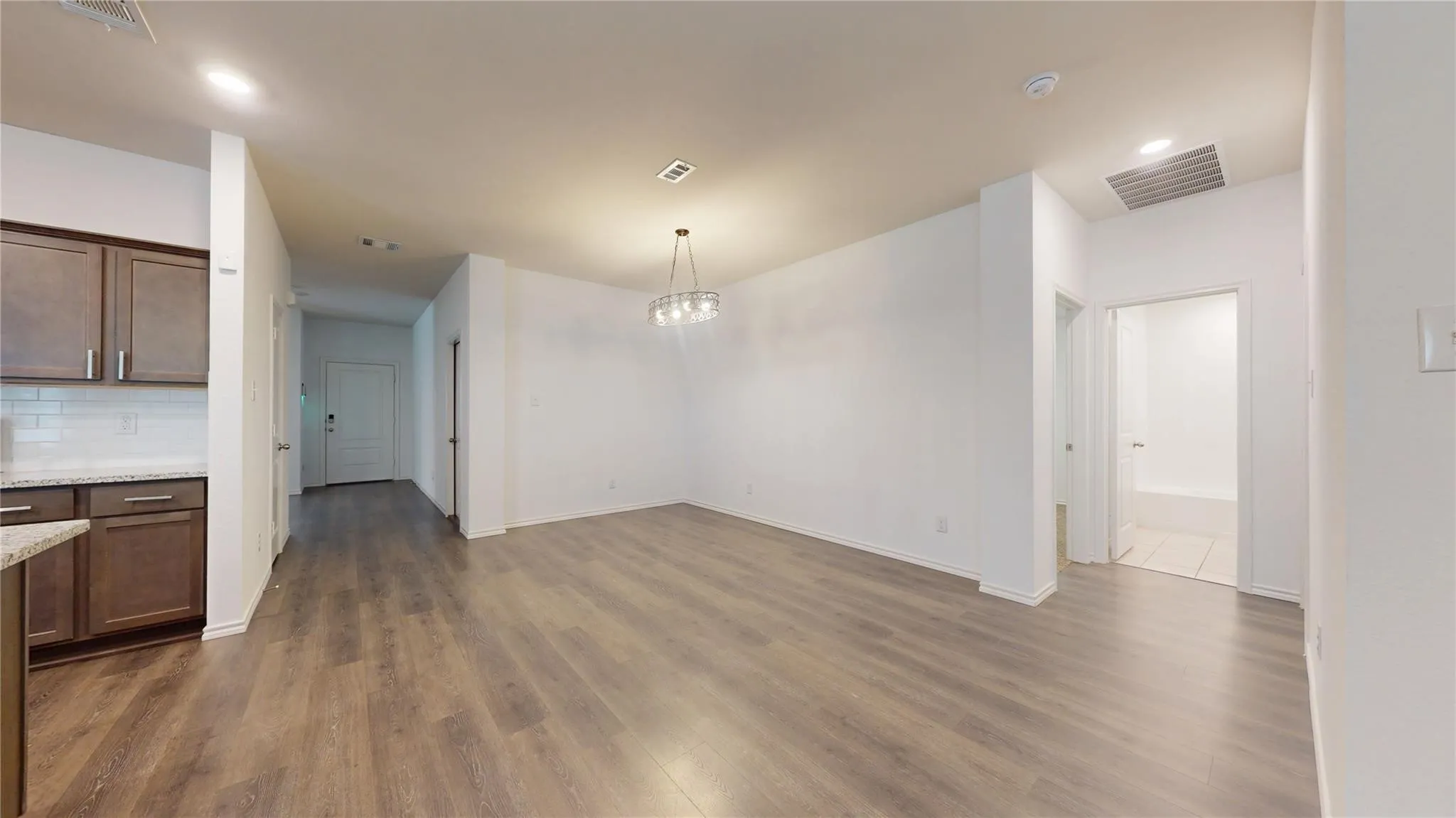 Open concept living area featuring wood-finish flooring and a contemporary chandelier