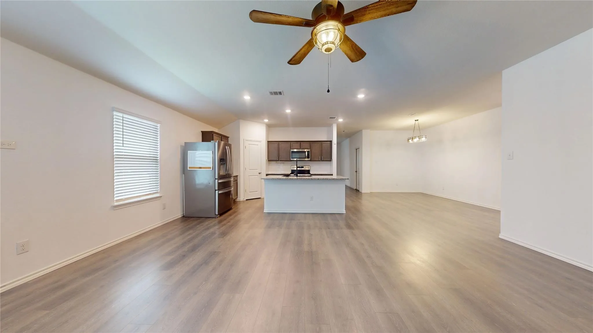 Open-concept living area featuring wood-finish flooring, recessed lighting, and a ceiling fan
