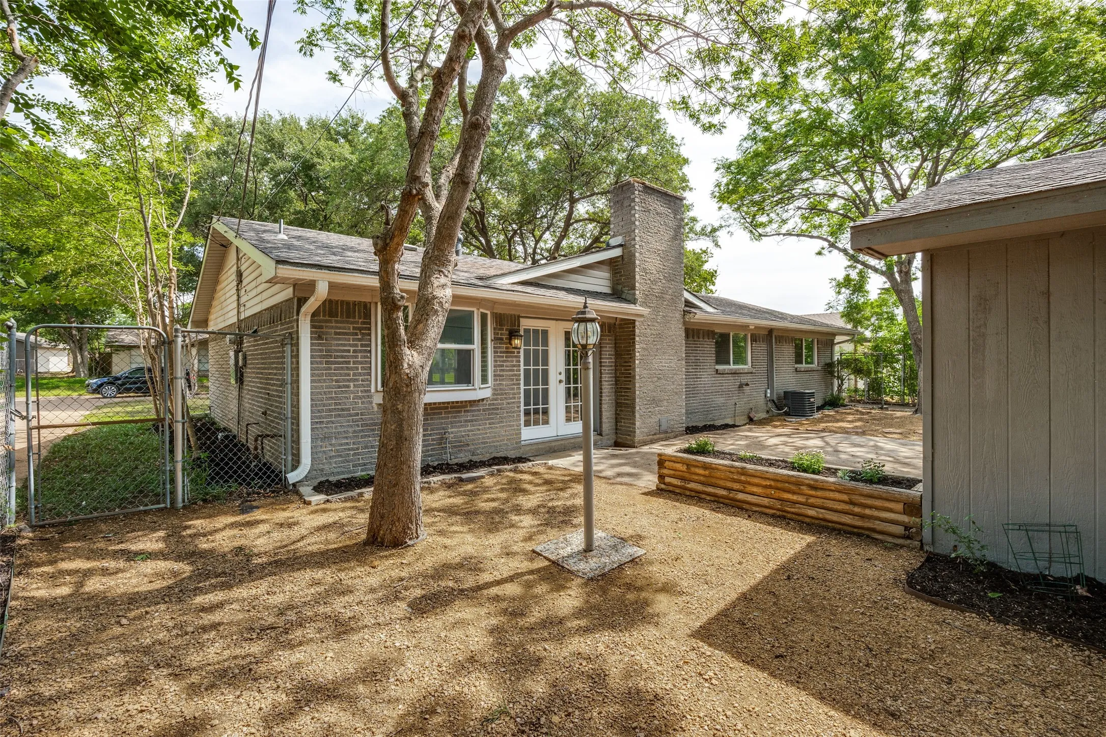 Rear exterior featuring light grey brick, a prominent brick chimney, and a gravel-covered yard