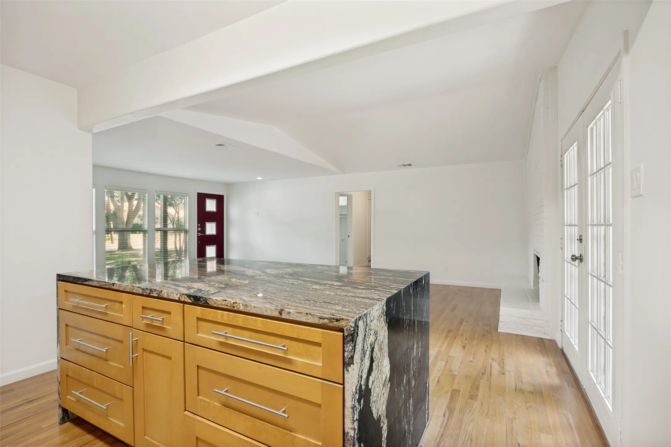 Kitchen island featuring wood cabinetry with stainless steel pulls and a granite countertop