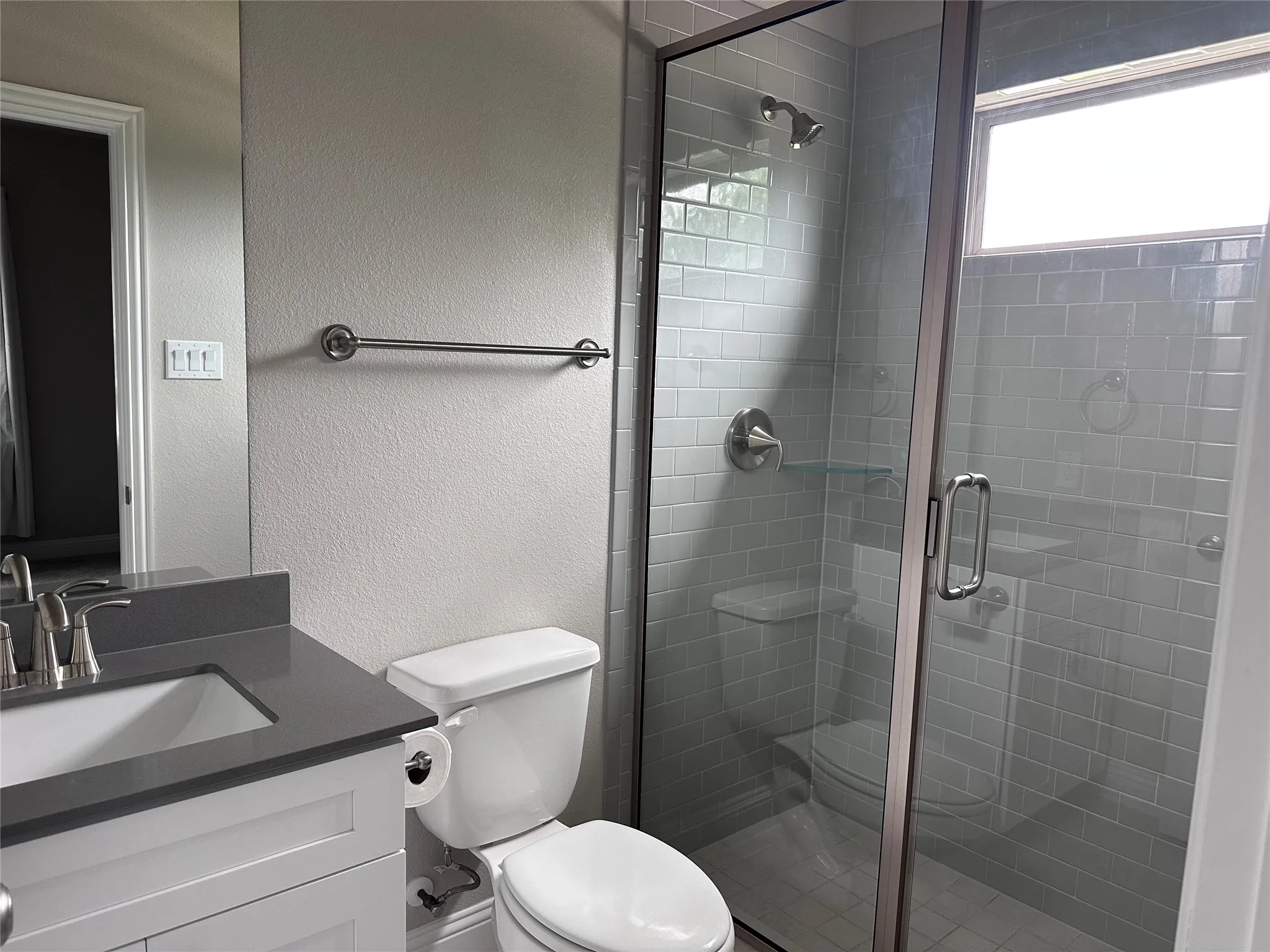 Glass-enclosed shower with subway tile surround, integrated shelving, and brushed nickel fixtures