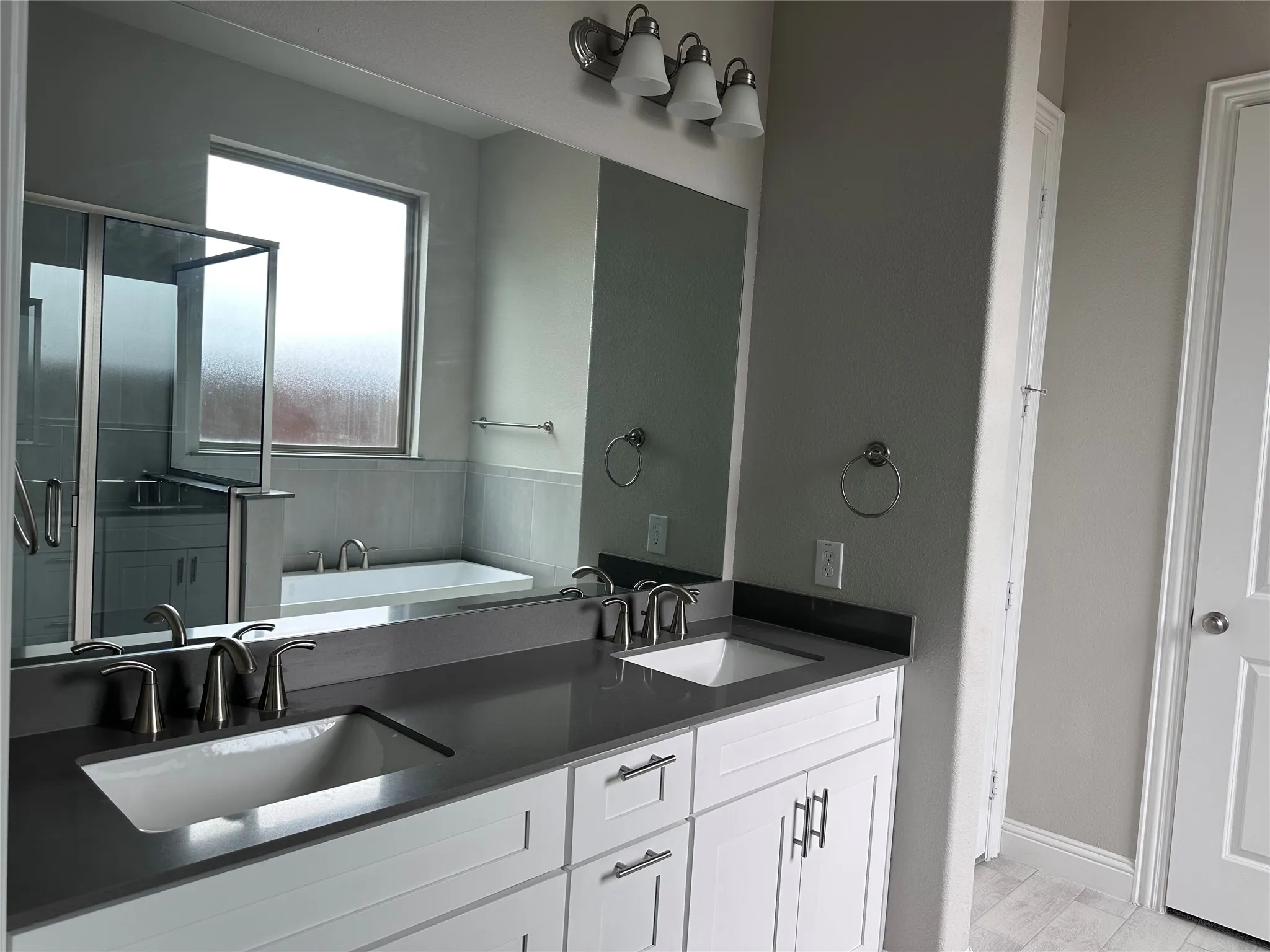 Dual vanity with white cabinetry, dark countertops, and brushed nickel fixtures