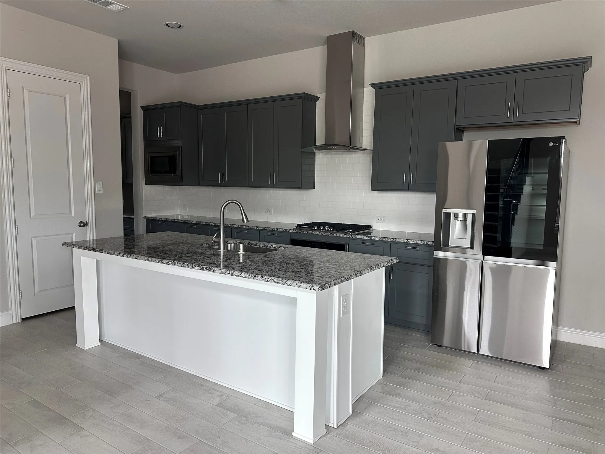 Kitchen featuring a spacious island with a built-in sink and granite countertop