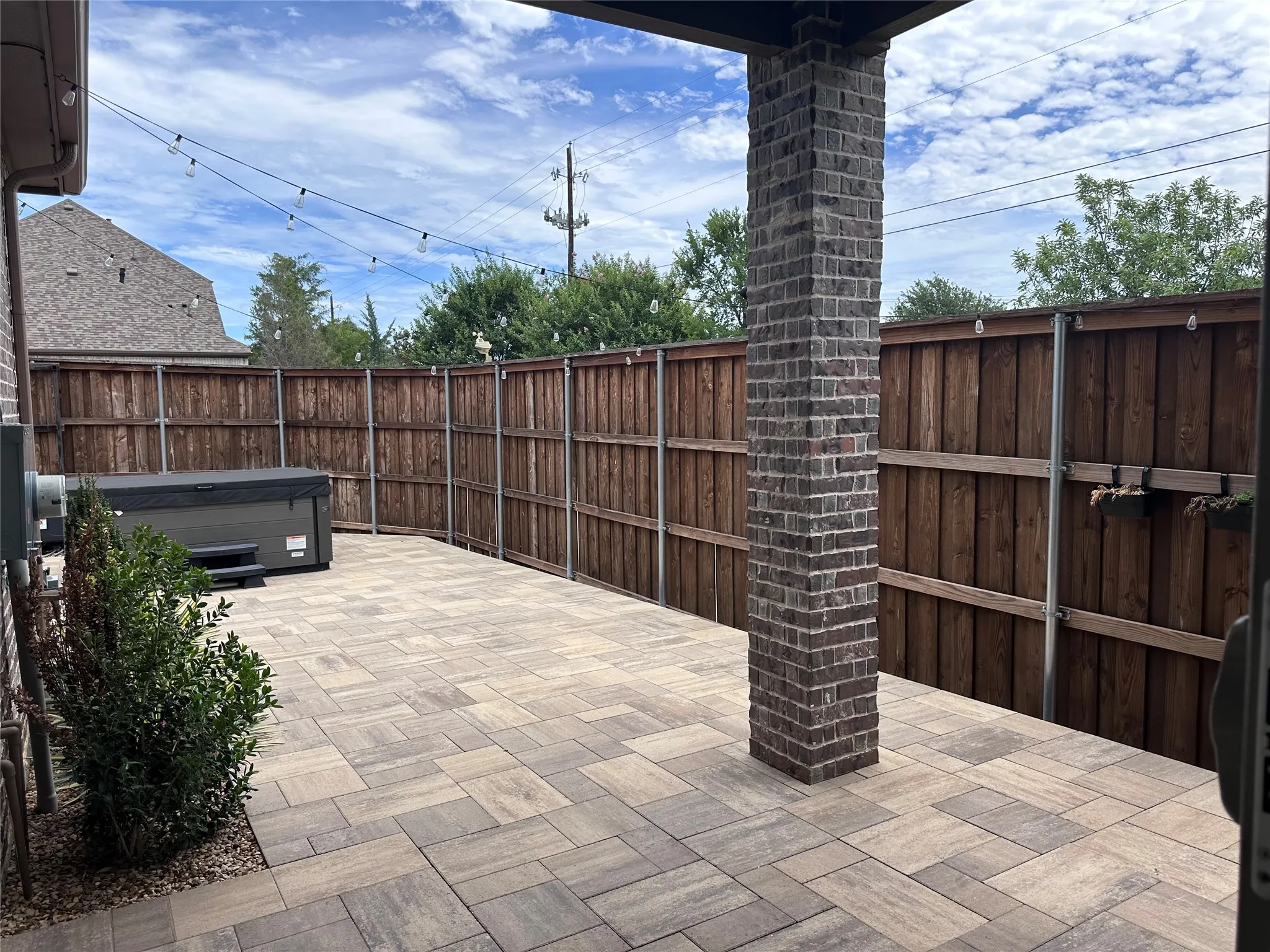 Expansive paver patio featuring a brick column and perimeter fencing