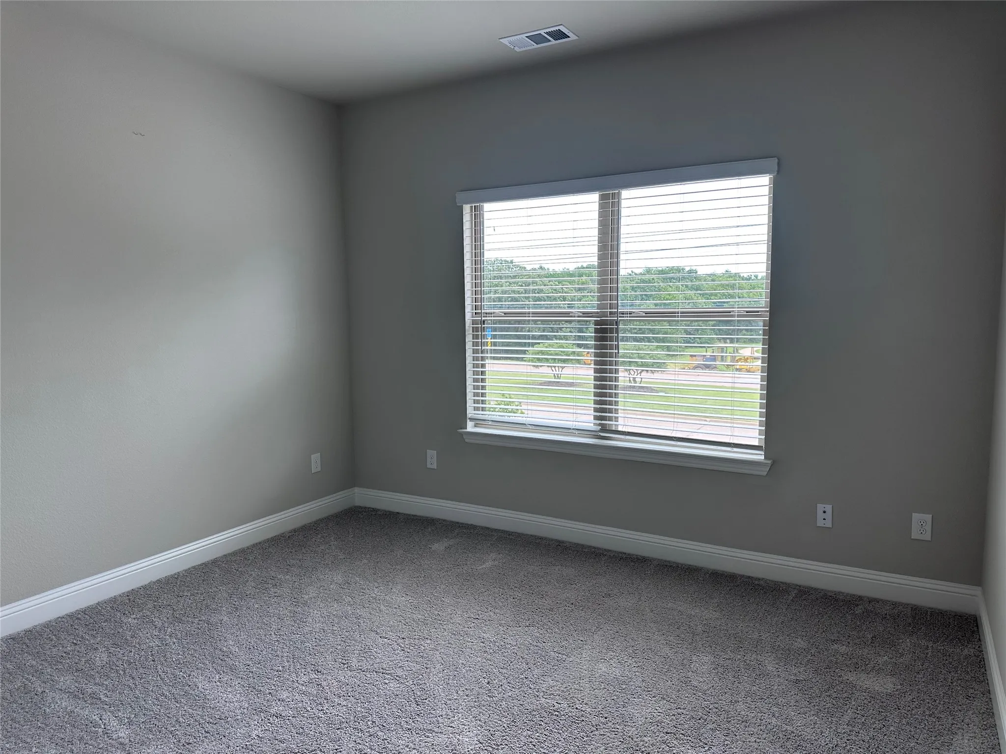 Neutral-toned interior room with gray carpet flooring and white baseboards