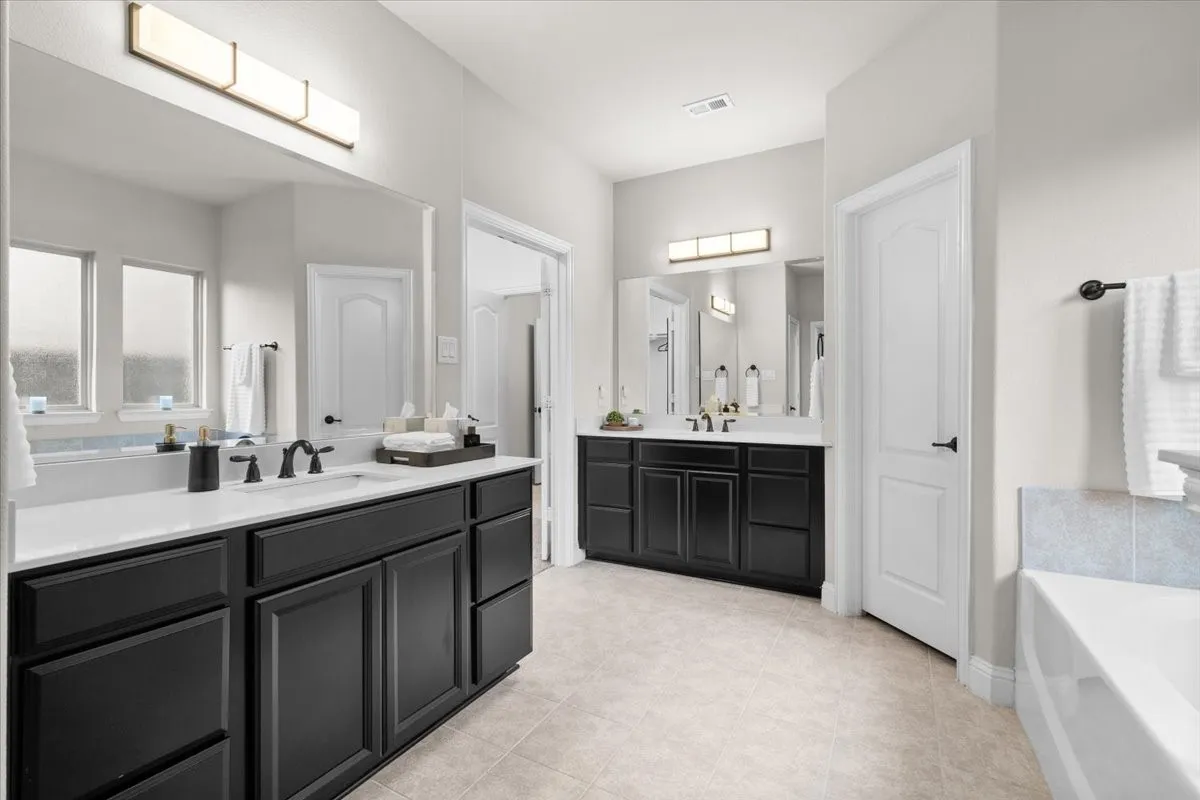 Spa-inspired primary bath with dual vanities, soaking tub, and separate shower