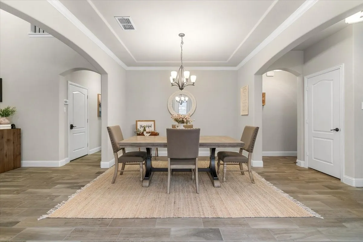 Elegant formal dining room with tray ceiling and arched entryways