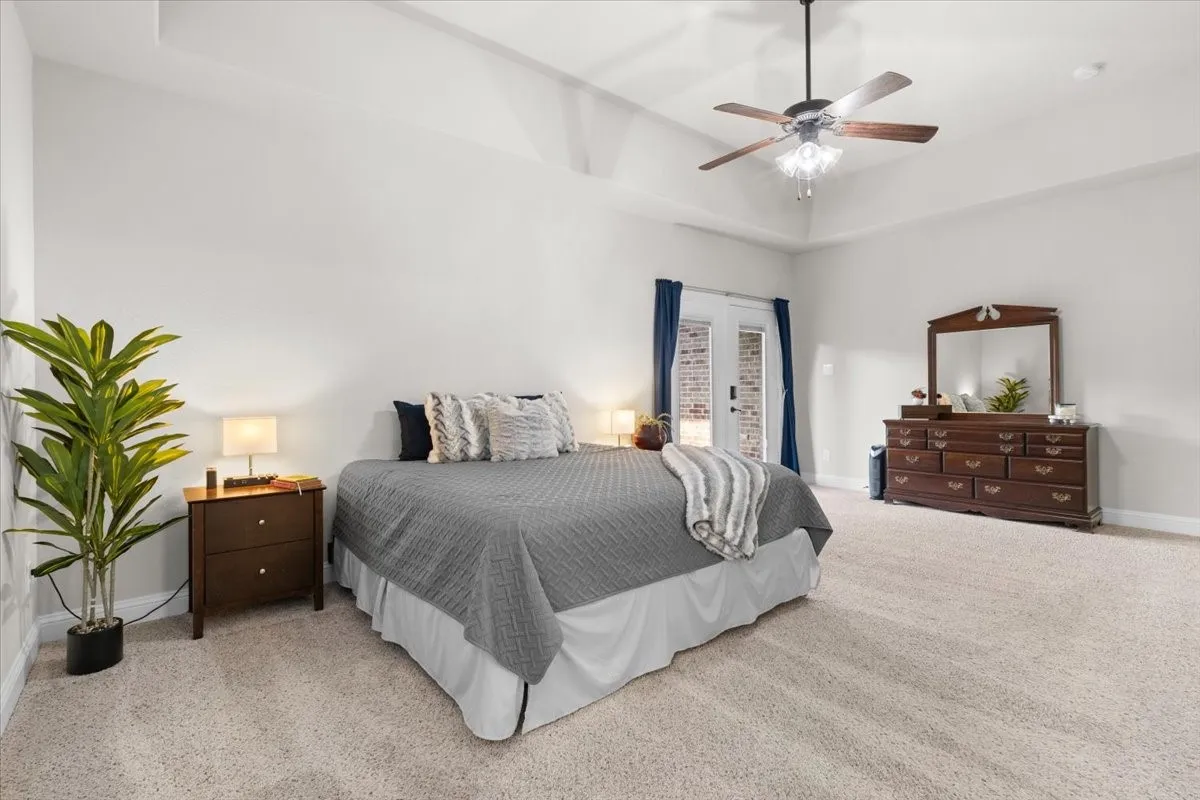 Spacious primary suite with tray ceiling and private patio access
