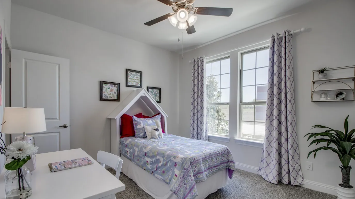 Bedroom featuring neutral wall tones, carpet flooring, a ceiling fan, and two windowpanes with window treatments