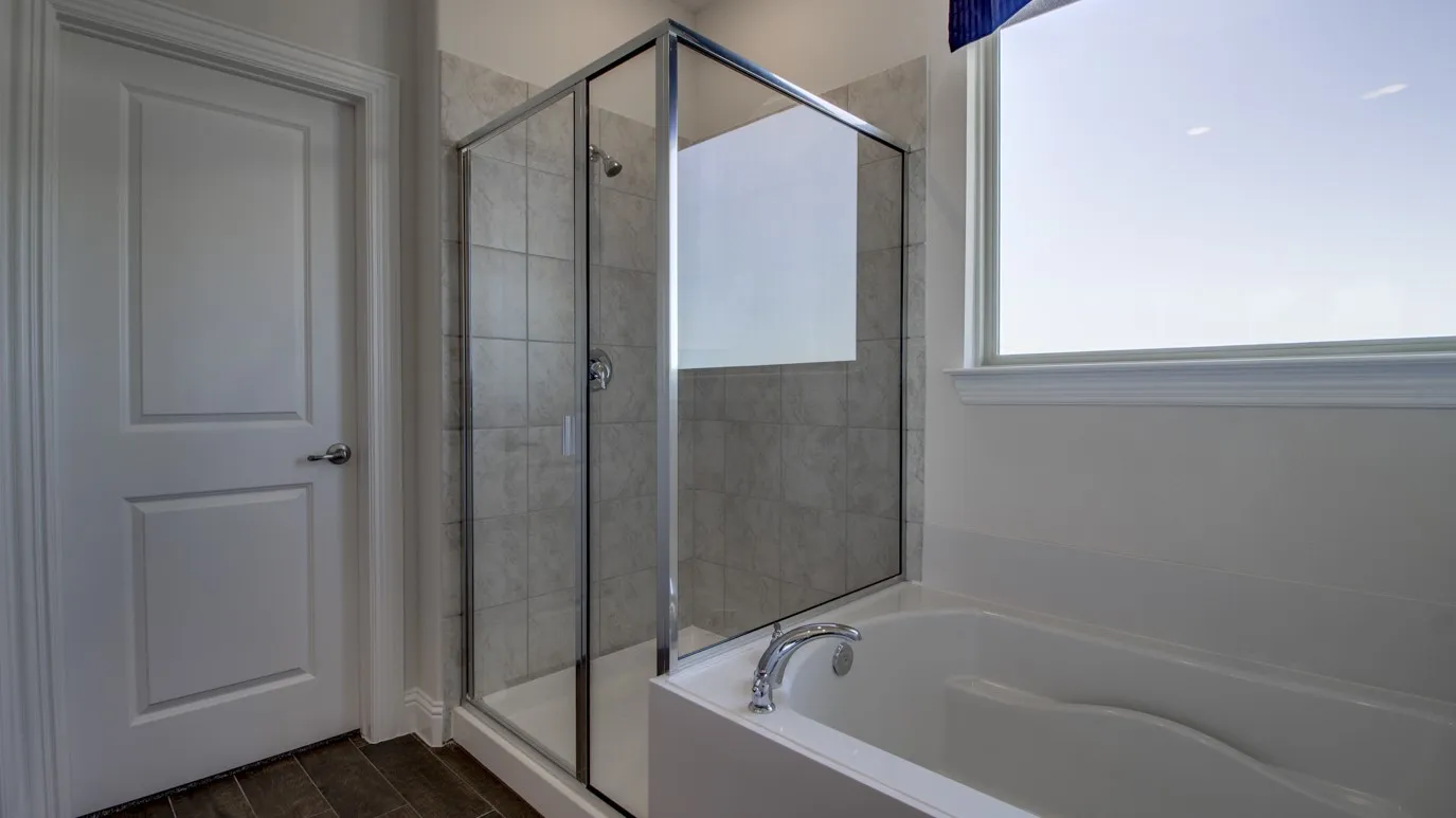 Bathroom featuring a glass-enclosed shower with tile surround, a built-in tub with chrome fixtures, and a large window
