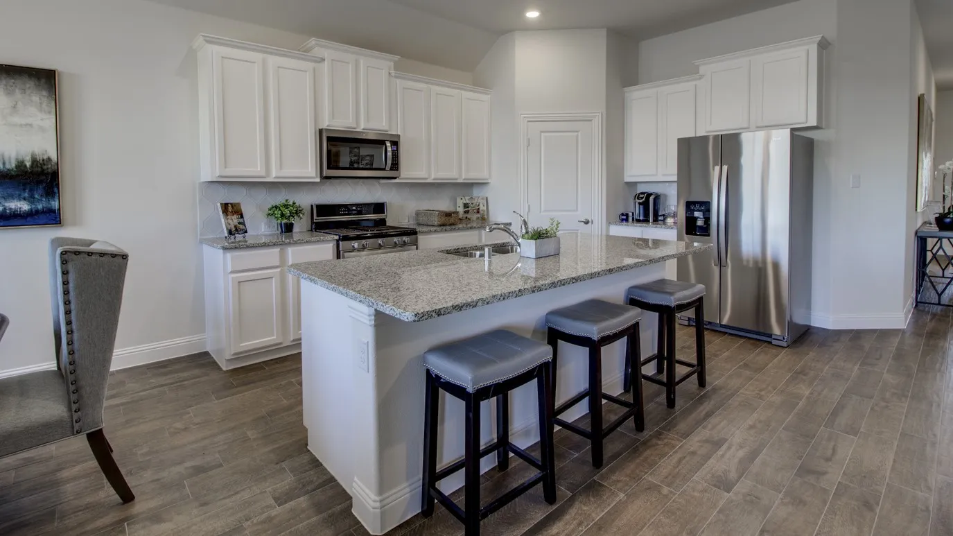 Open-concept kitchen featuring an oversized island with seating, granite countertops, white cabinetry, stainless steel appliances, and wood-finish flooring
