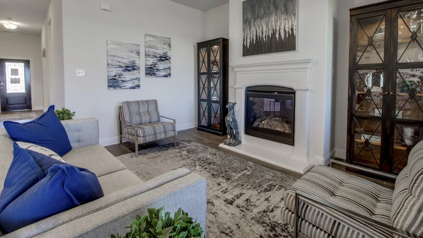 Living room featuring a fireplace with a white mantel, dark wood-finish flooring, and a decorative area rug