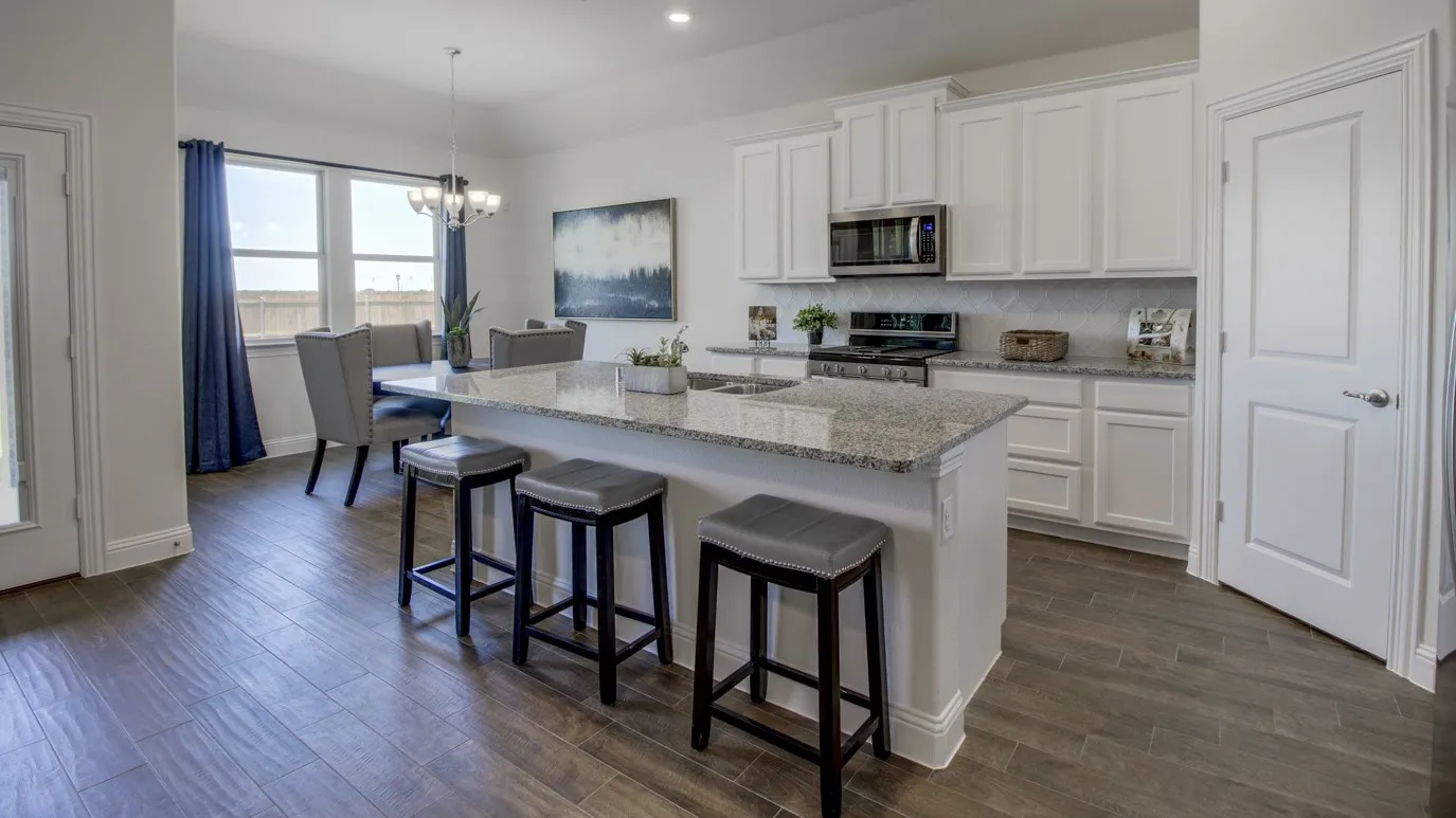 Modern kitchen featuring white shaker cabinetry, stainless steel appliances, a tile backsplash, and a granite island with breakfast bar seating