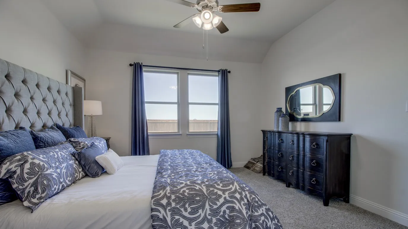 Carpeted room featuring two windows with blue drapery, a vaulted ceiling, and a ceiling fan with light fixture
